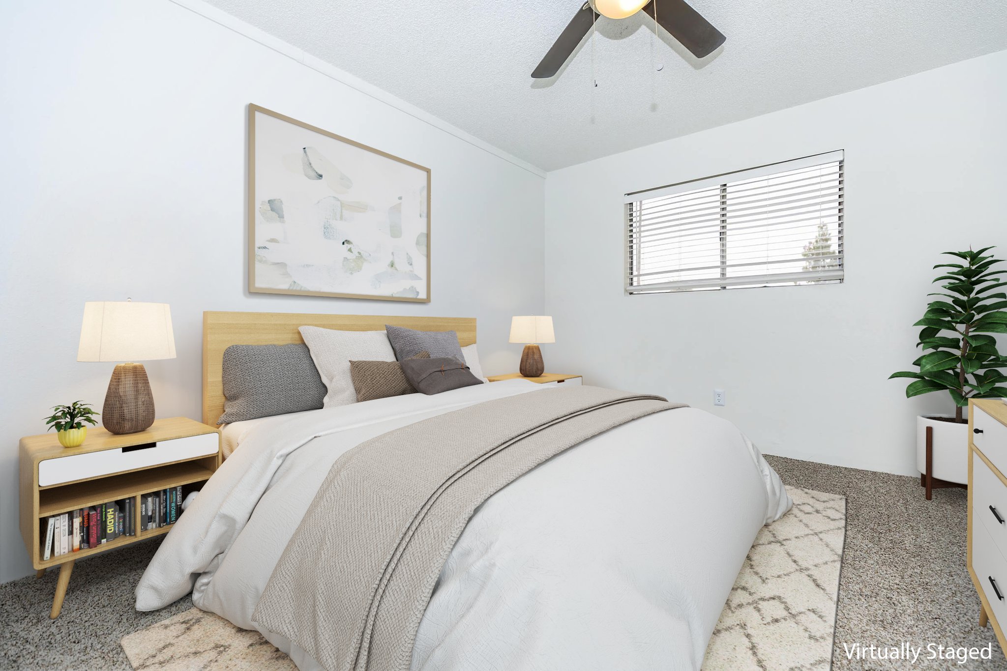 A bright and inviting bedroom featuring a queen-sized bed with a light gray comforter, decorative pillows, and a wooden headboard. There are bedside tables with lamps, a window allowing natural light, and a small indoor plant. The walls are painted white, and the floor is carpeted in neutral tones.