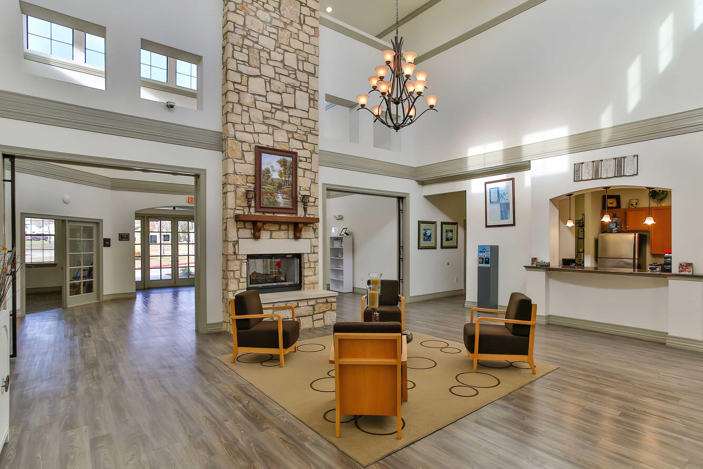 Spacious indoor lobby with high ceilings, featuring a stone fireplace and modern chandelier.