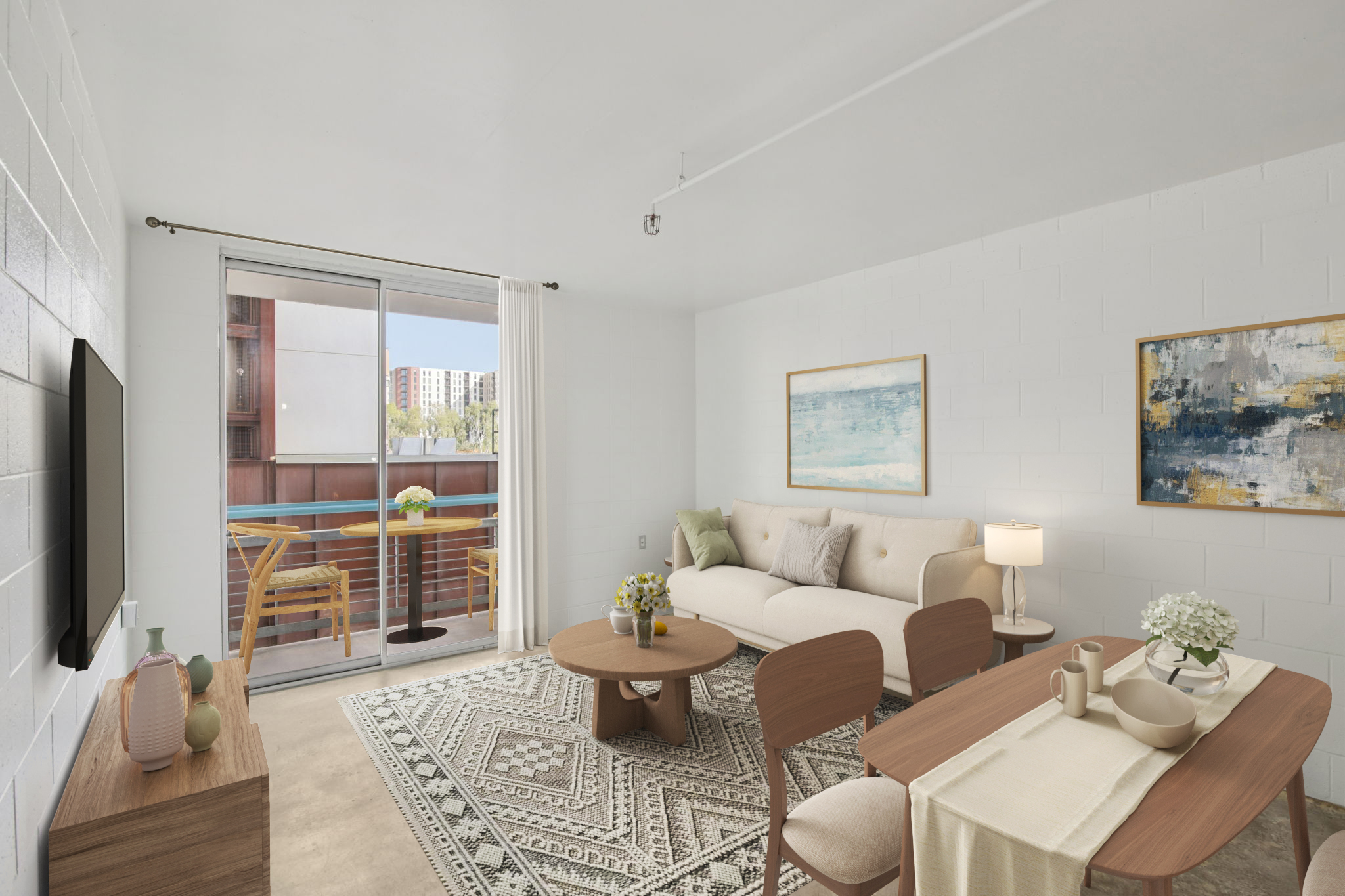 A cozy living room featuring a light-colored sofa, round coffee table, and a dining area with wooden chairs. A television is mounted on the wall, and large sliding glass doors lead to a balcony. Natural light fills the space, complemented by decorative artwork and a patterned area rug. A vase of flowers adds a touch of color.