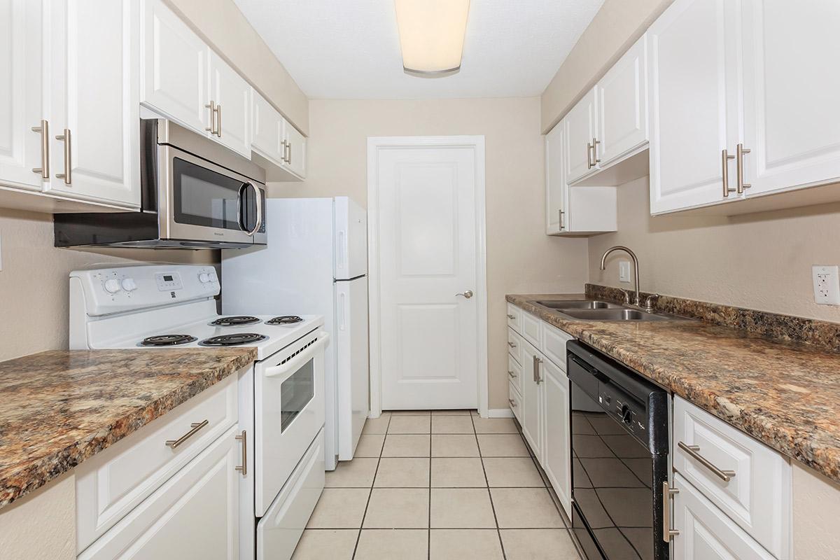 a kitchen with white cabinets and black counter