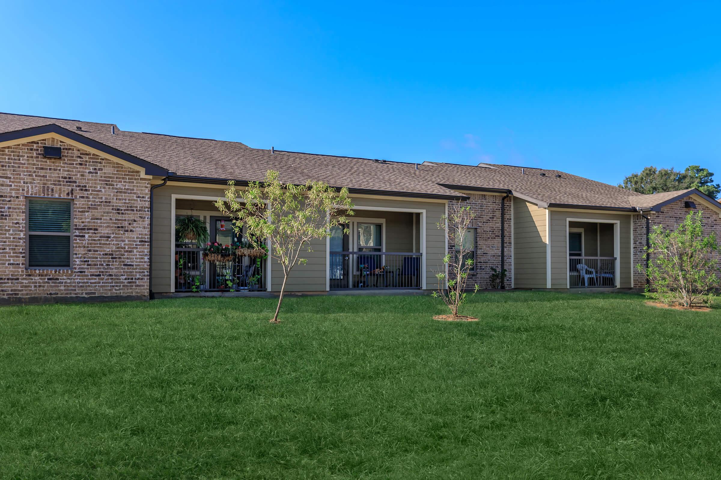 a large brick building with green grass in front of a house