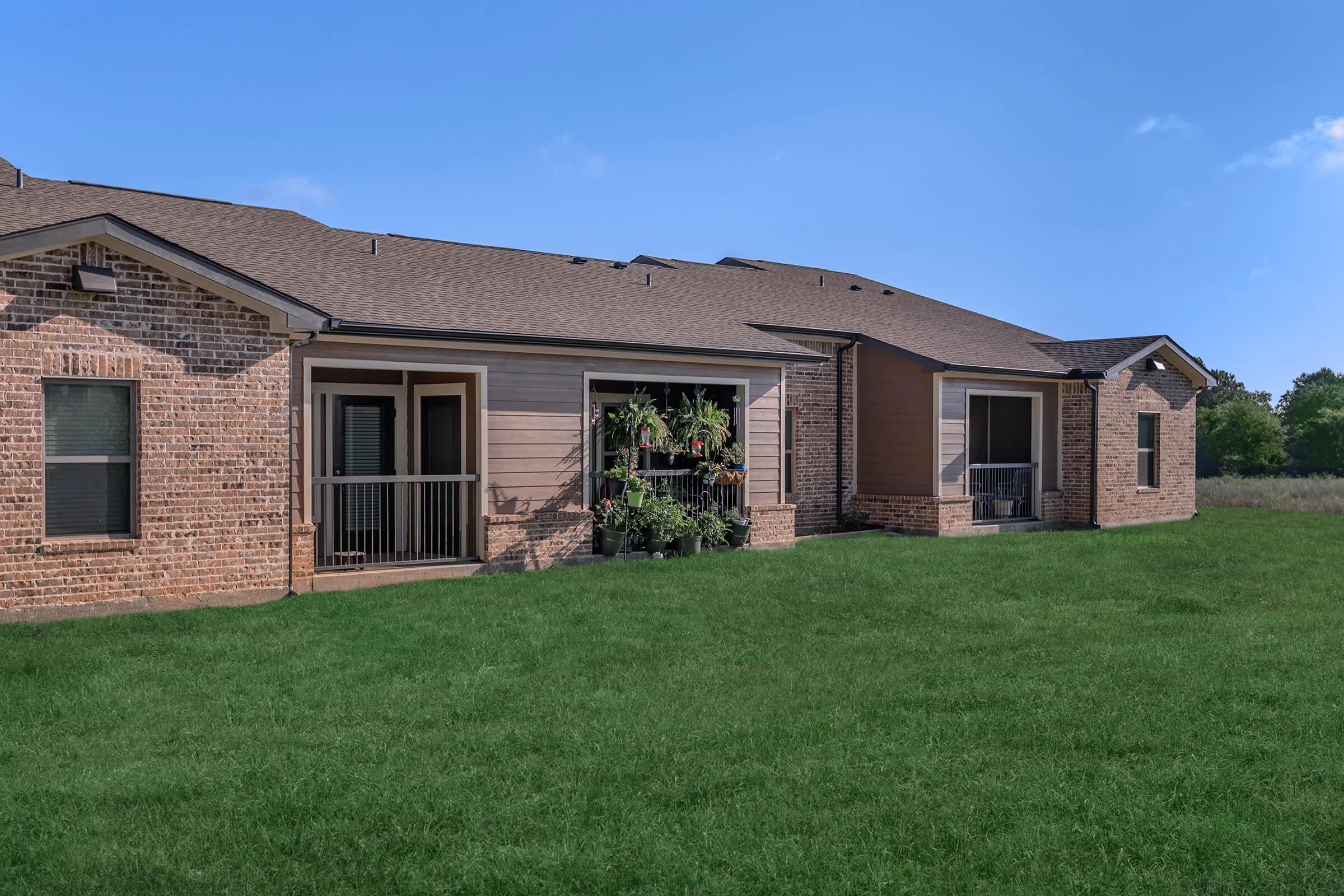 a large brick building with grass in front of a house