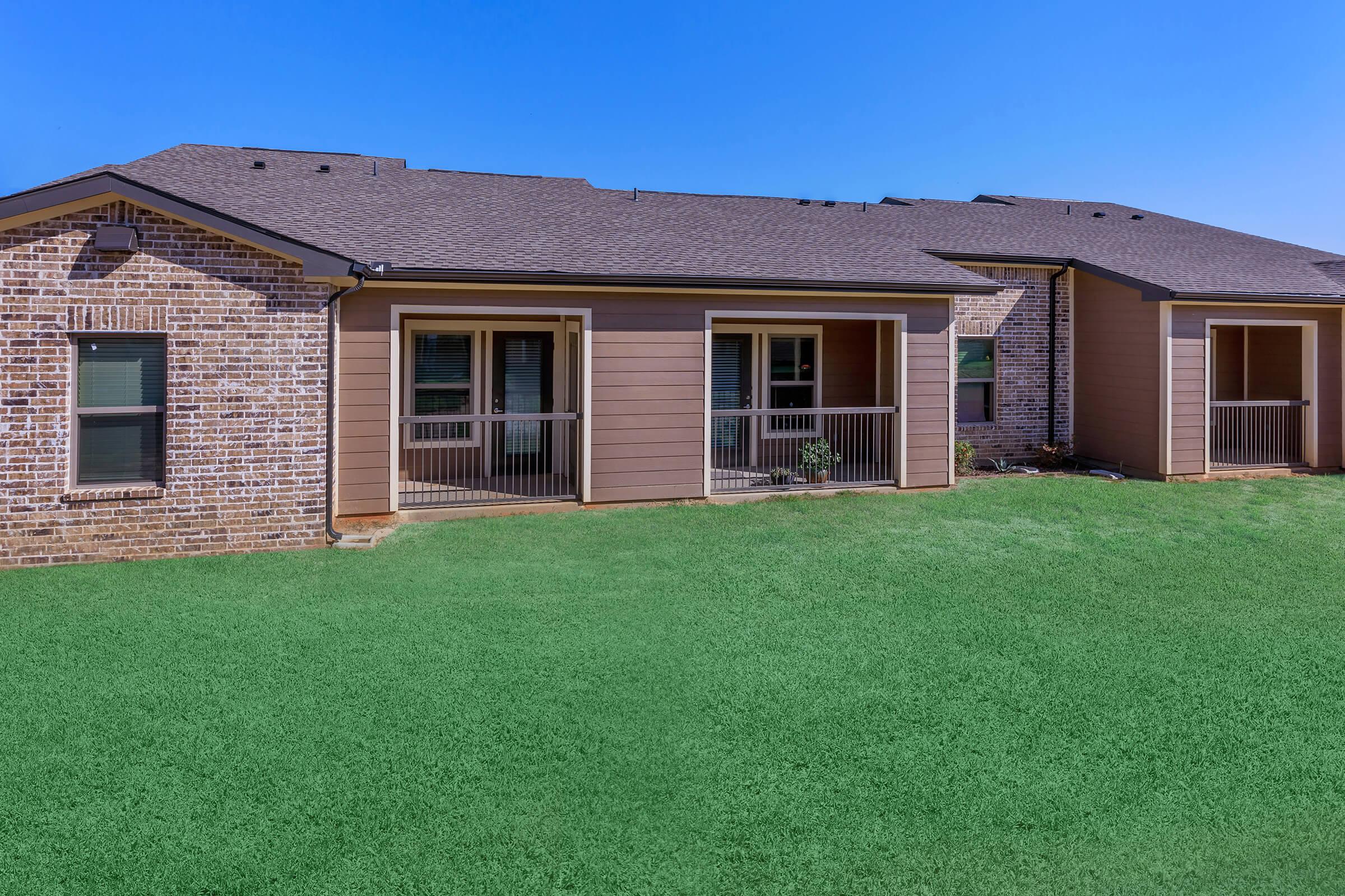 a large brick building with green grass in front of a house