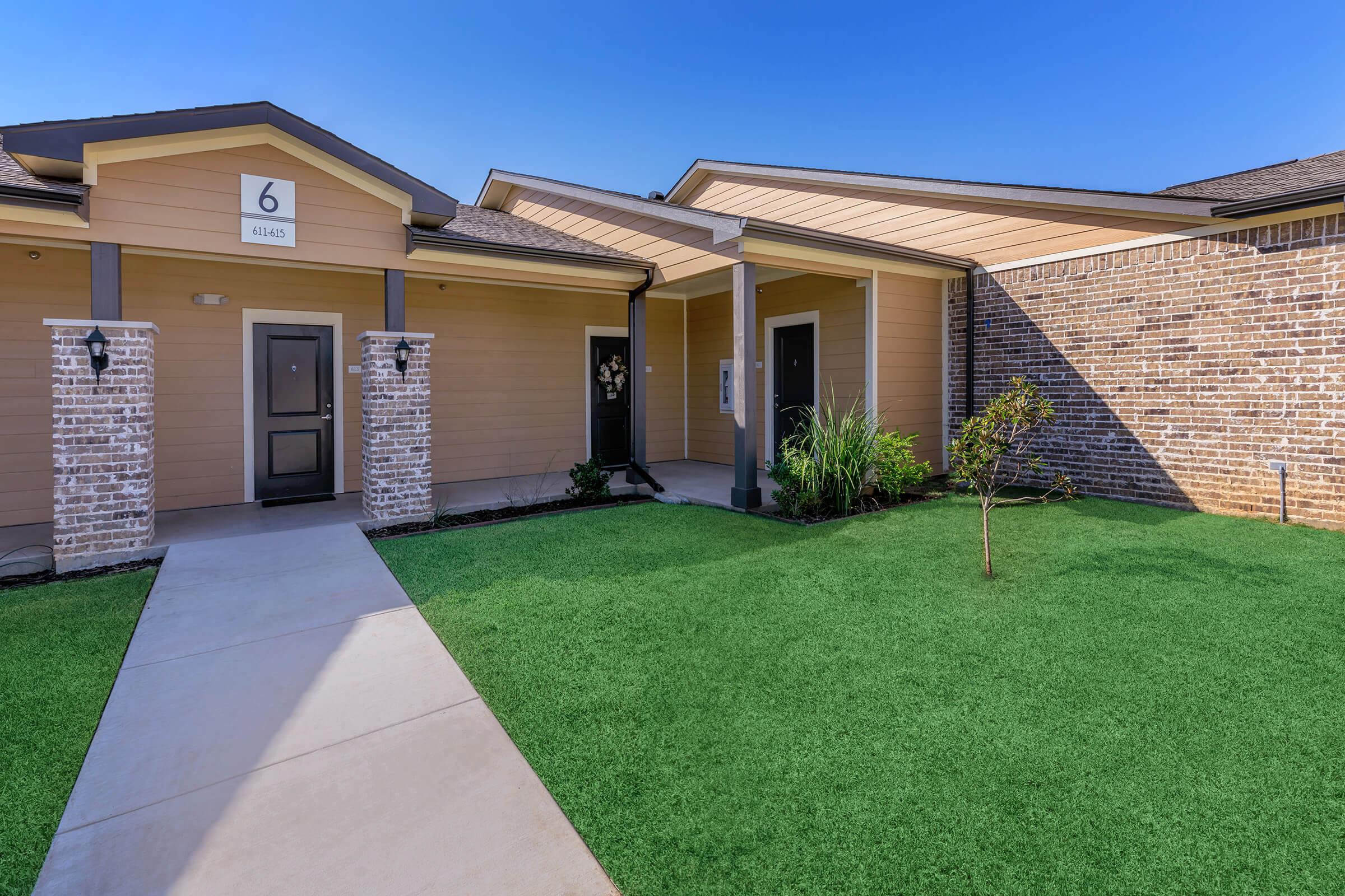 a house with a lawn in front of a brick building