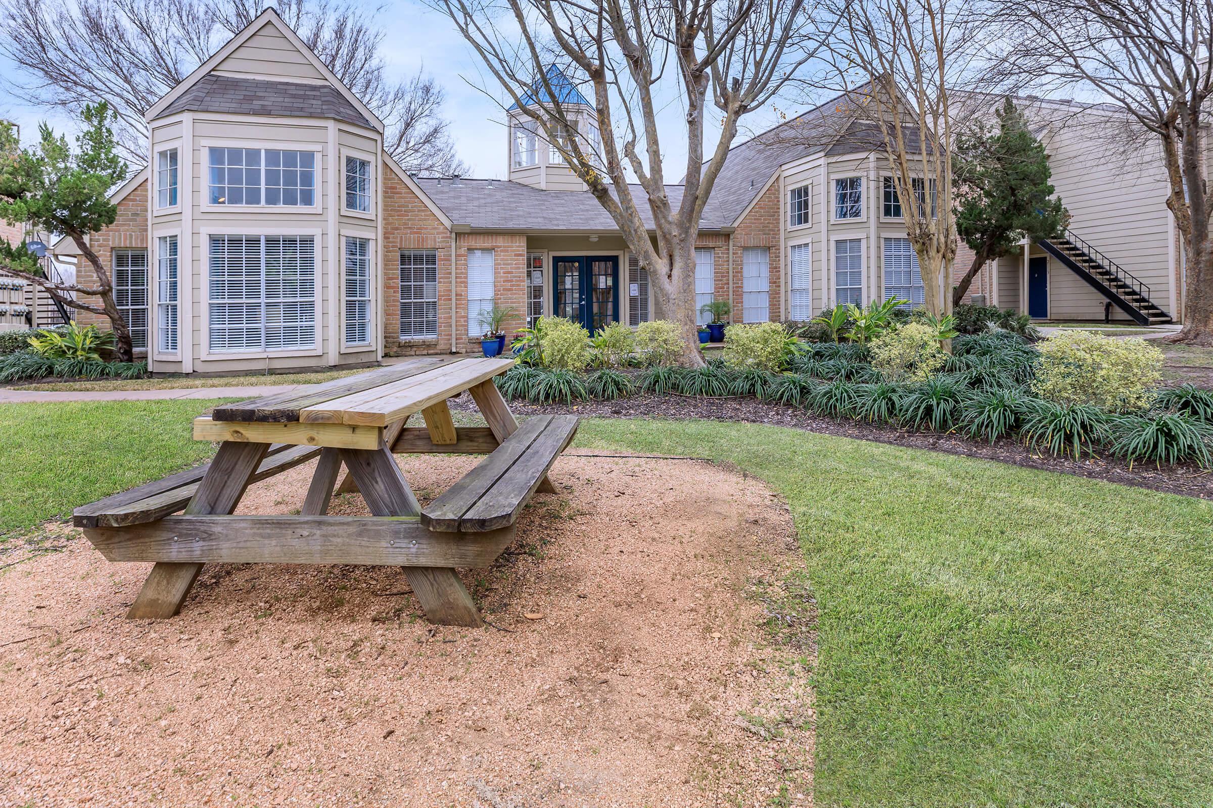 a wooden park bench sitting in front of a house