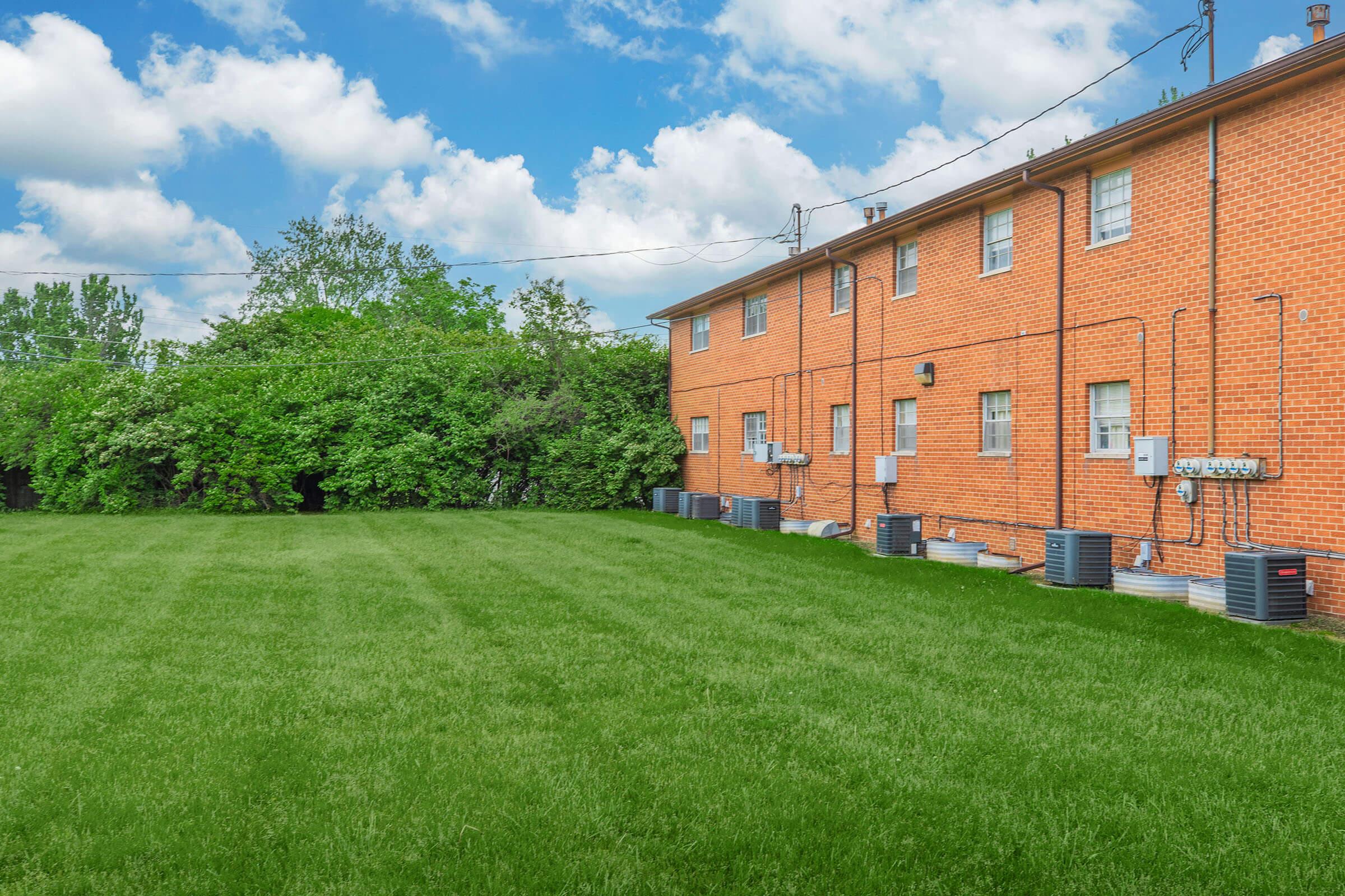 a large brick building with a grassy field