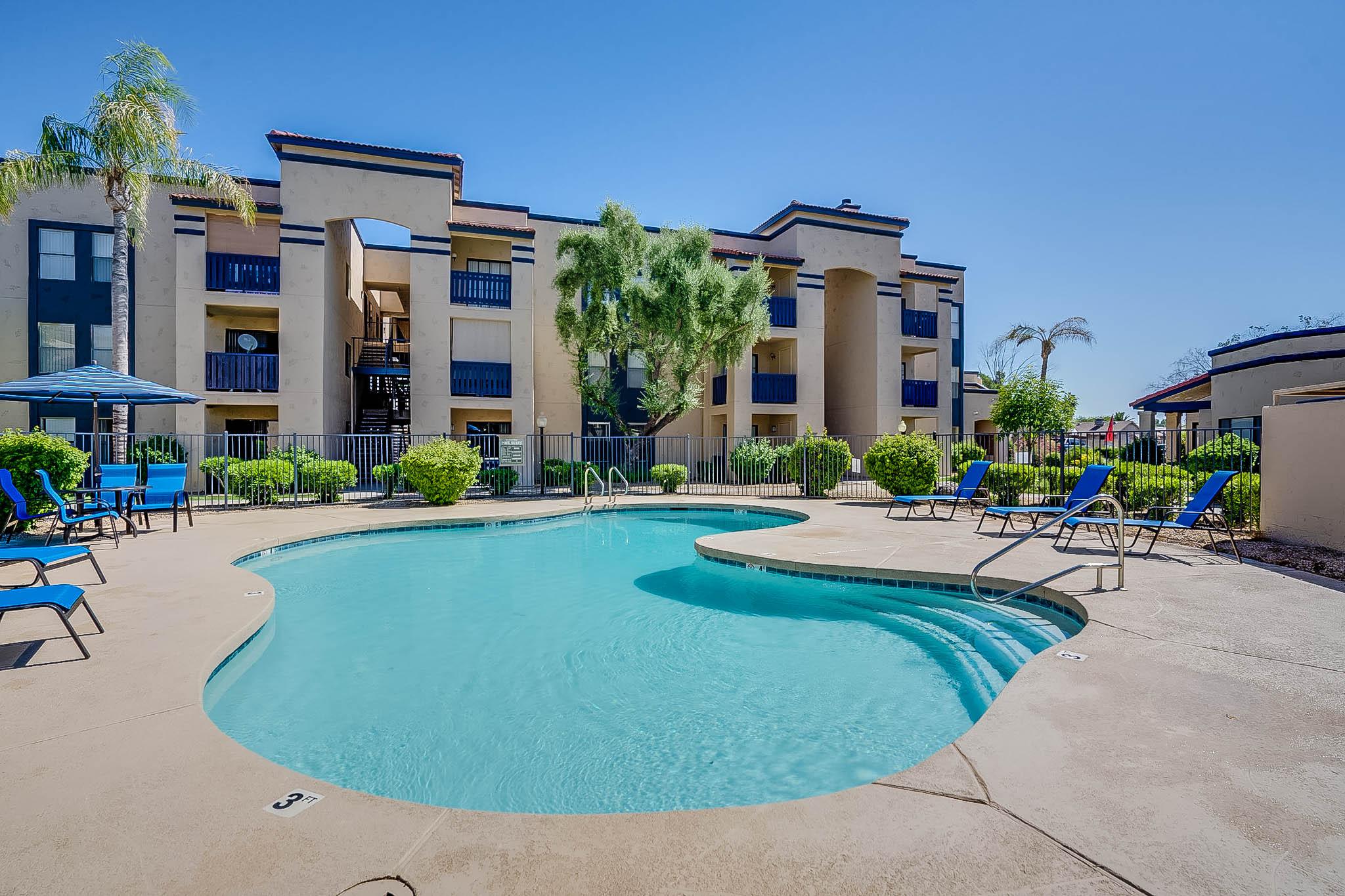 Phoenix AZ Apartments - Monaco31 - Pool With Clear Water, Lounge Chairs, and Metal Fence