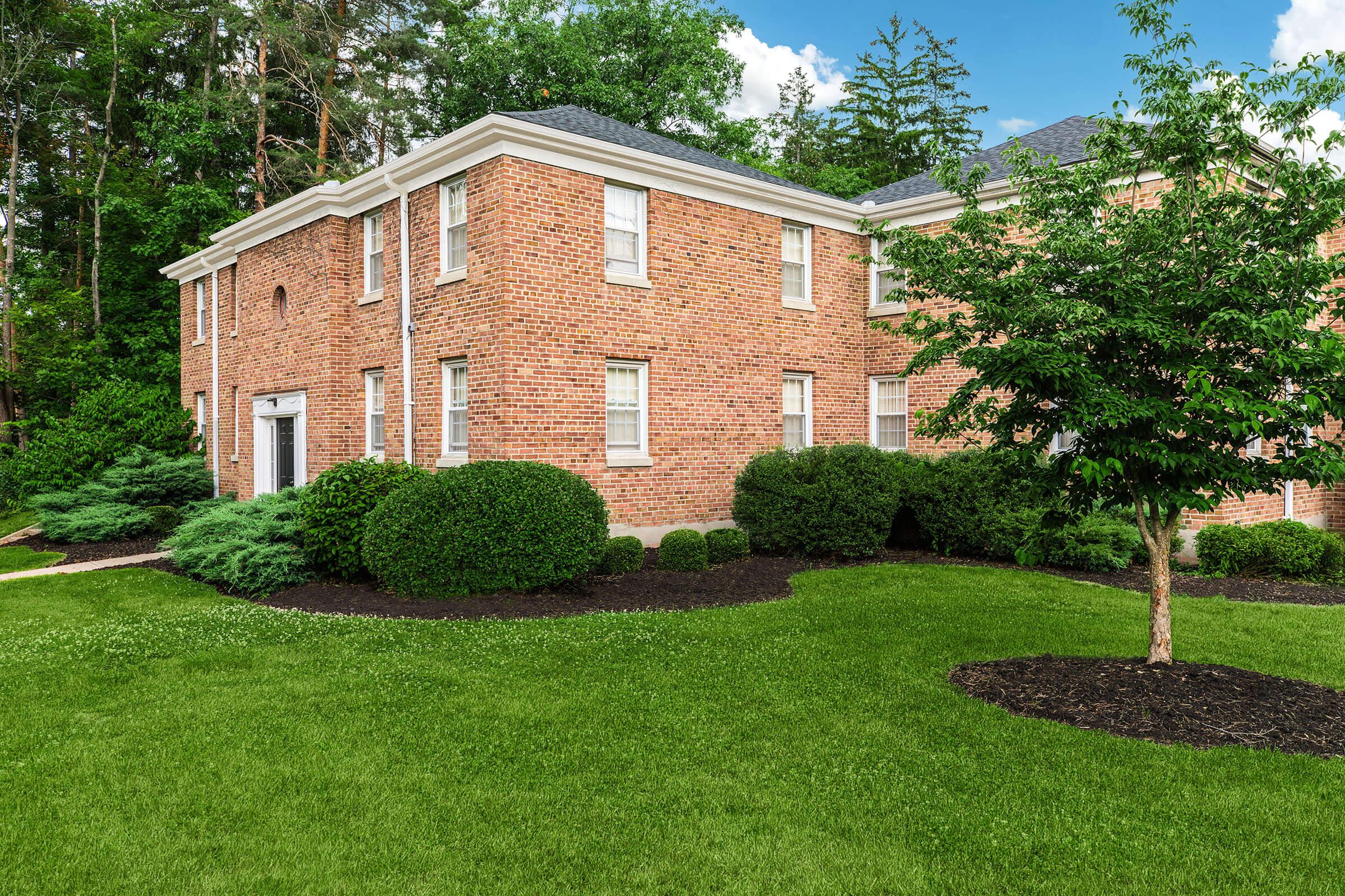 a large brick building with green grass in front of a house