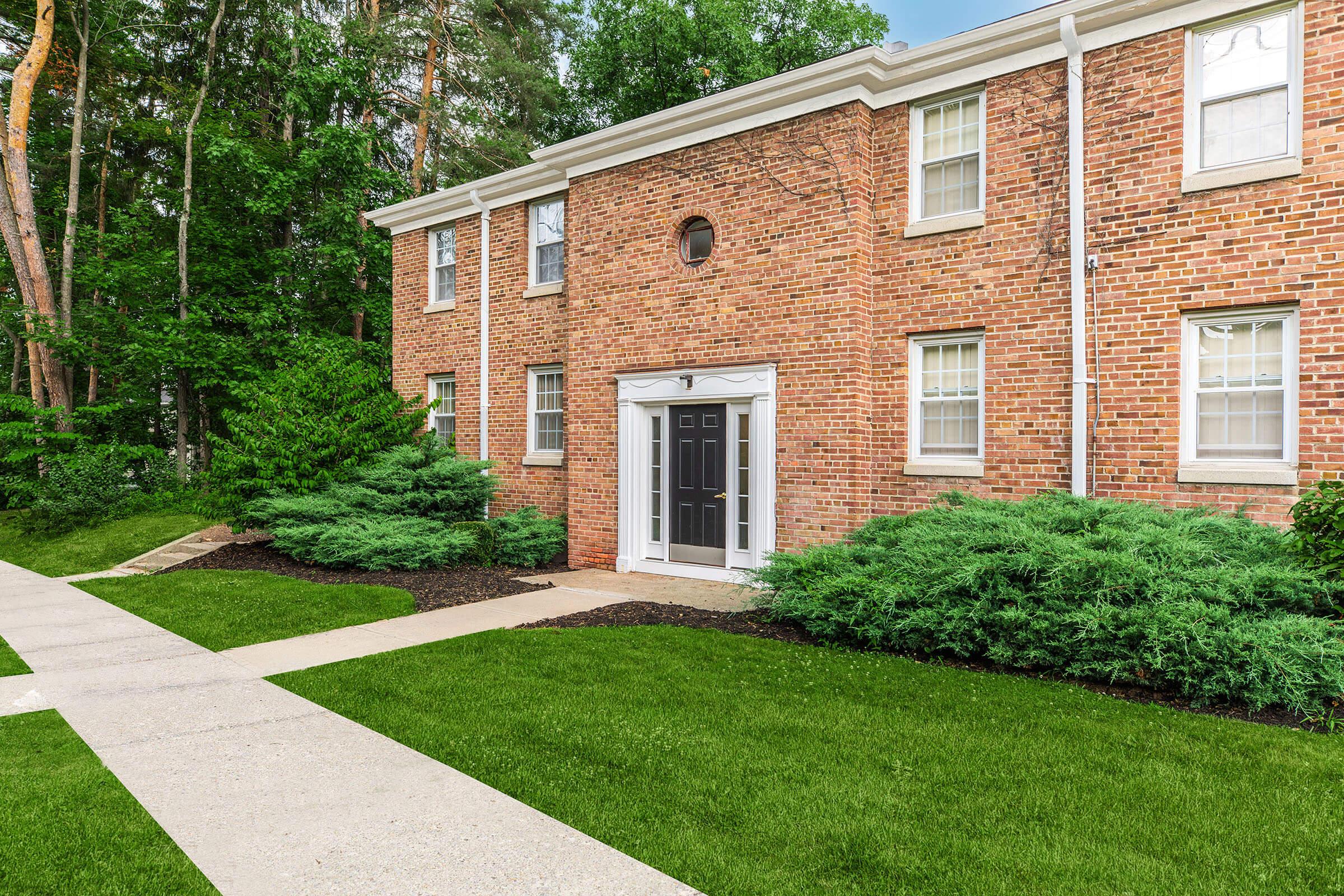 a large brick building with grass in front of a house