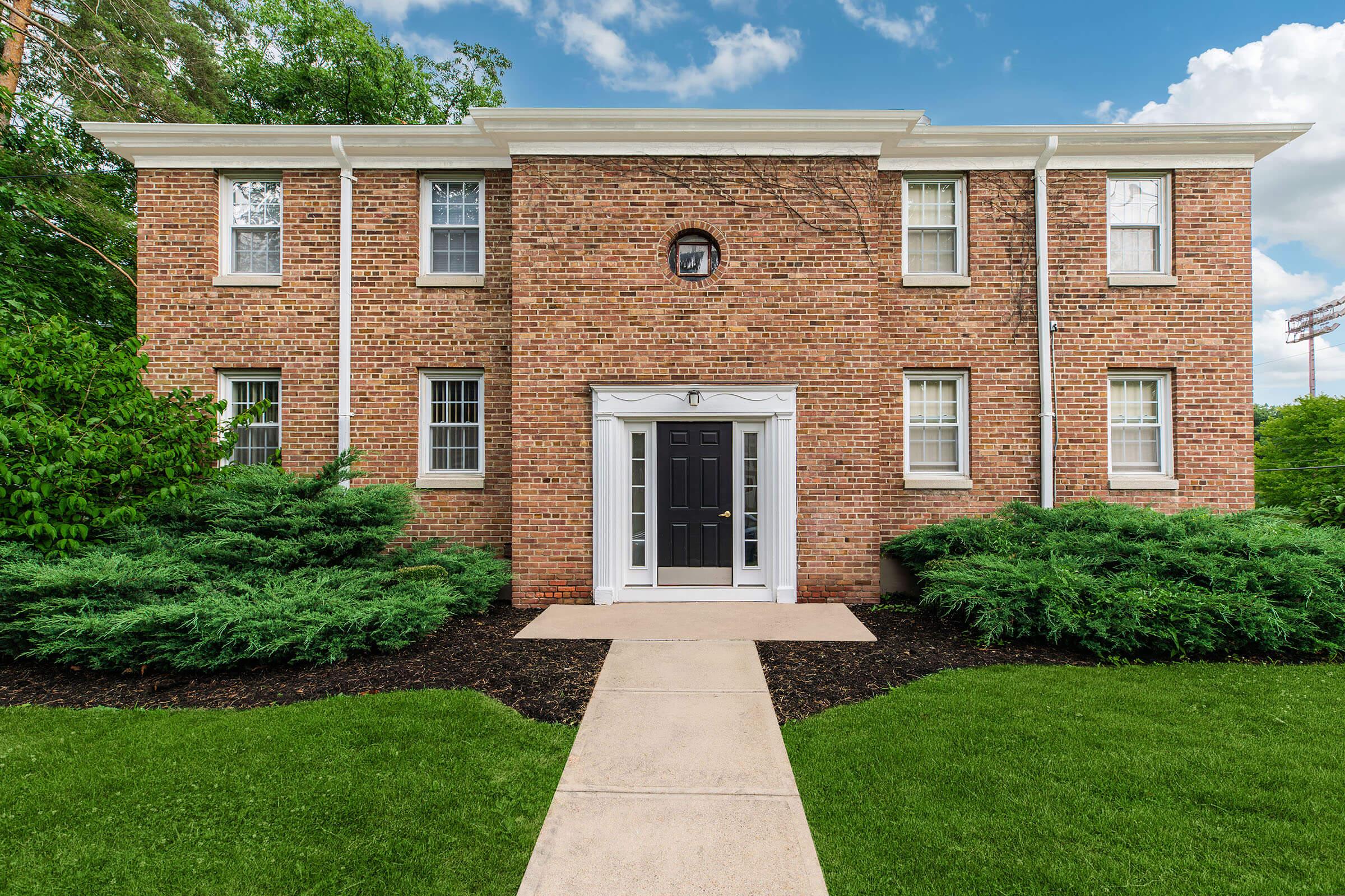 a large brick building with grass in front of a house