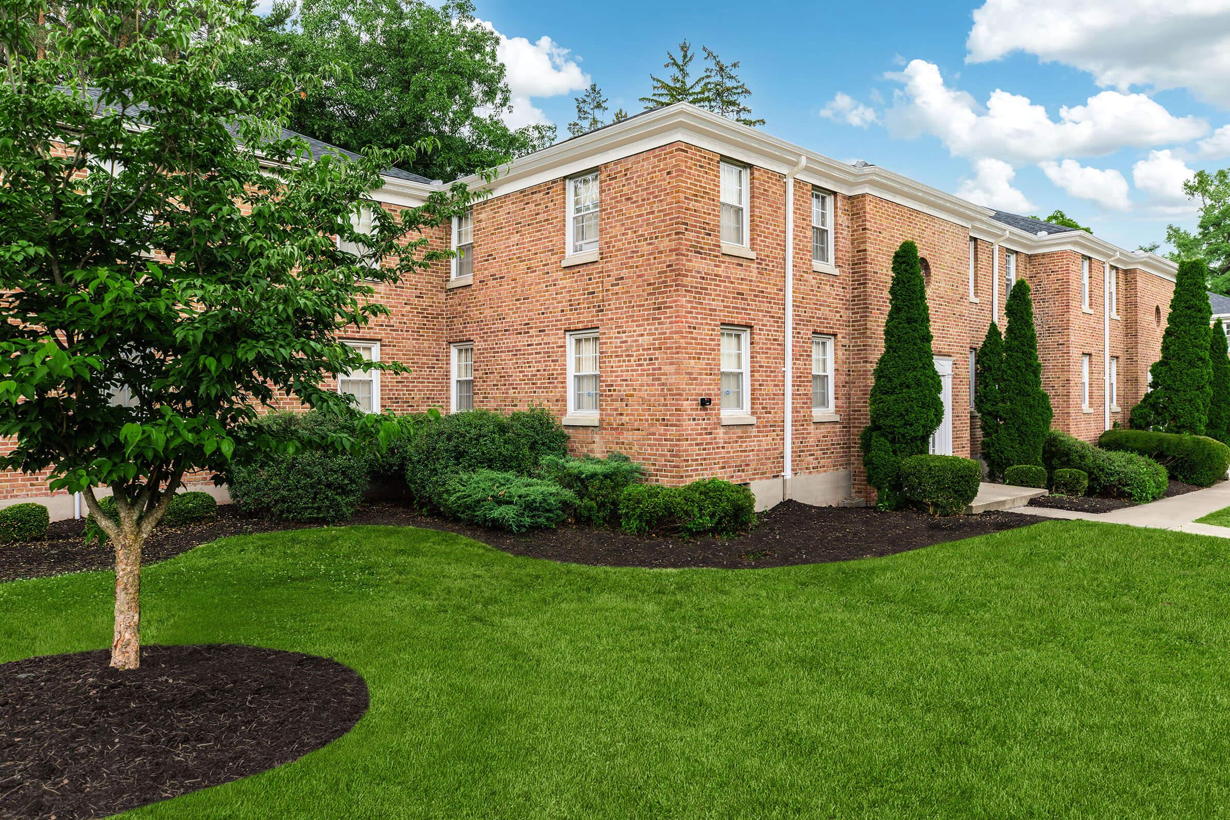 a large brick building with green grass