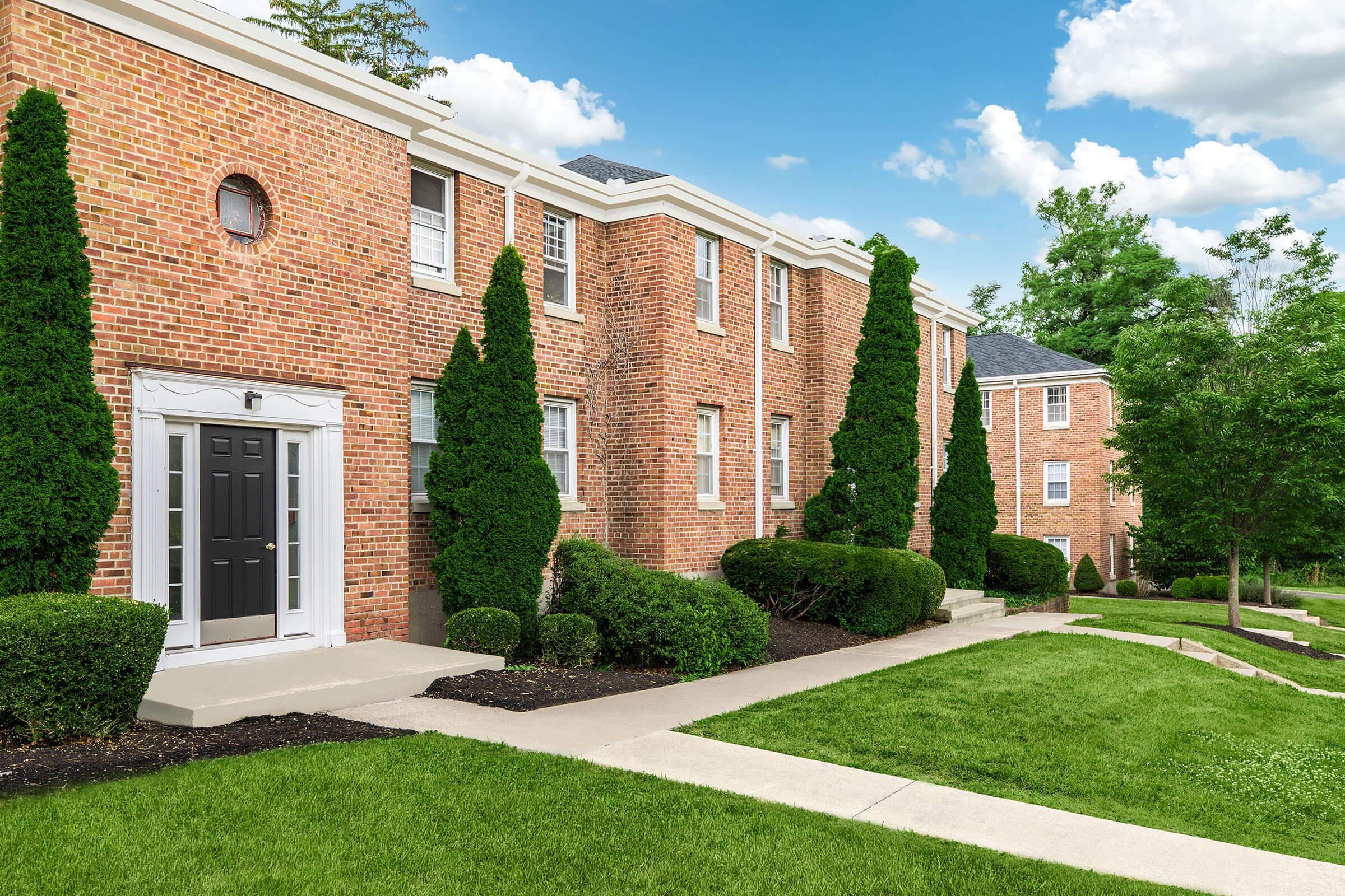 a large brick building with grass in front of a house