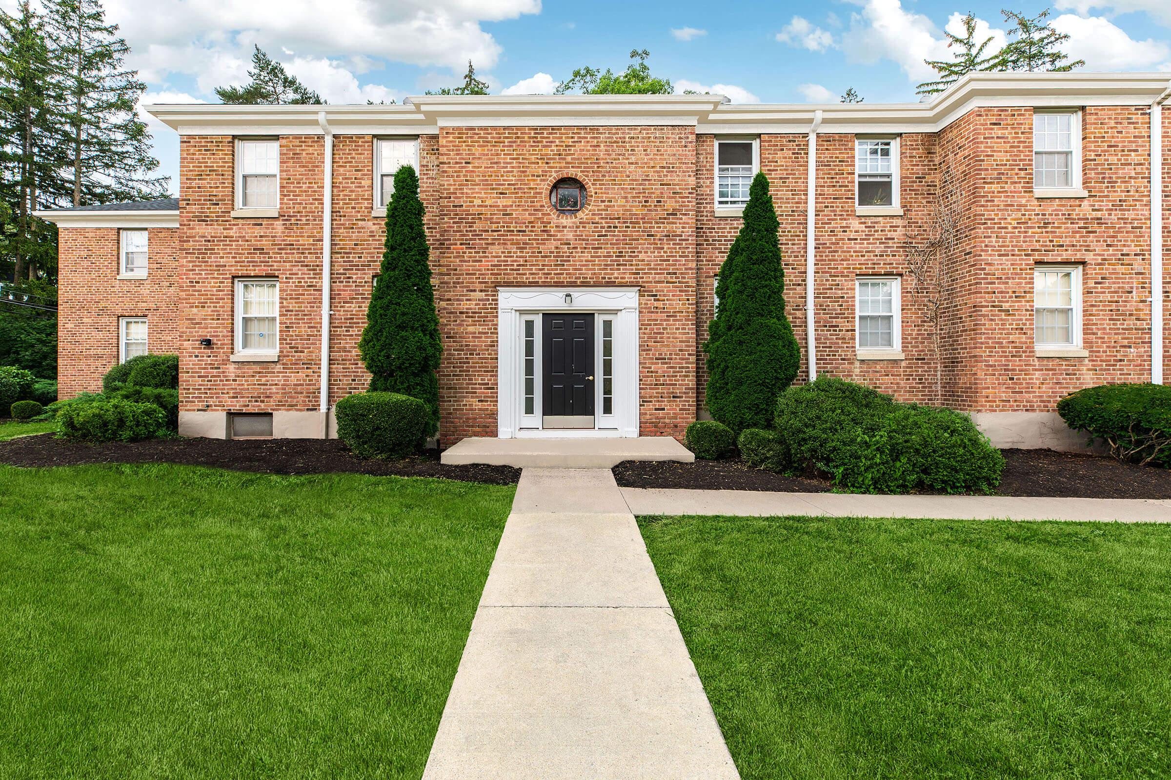 a large brick building with grass in front of a house