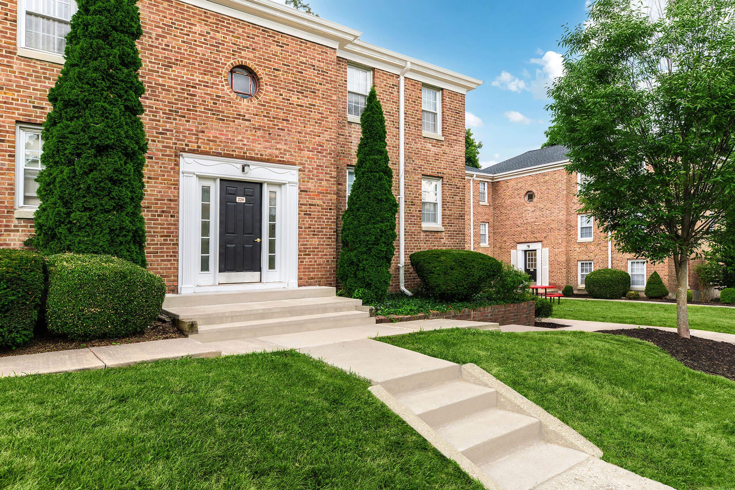 a large brick building with grass in front of a house