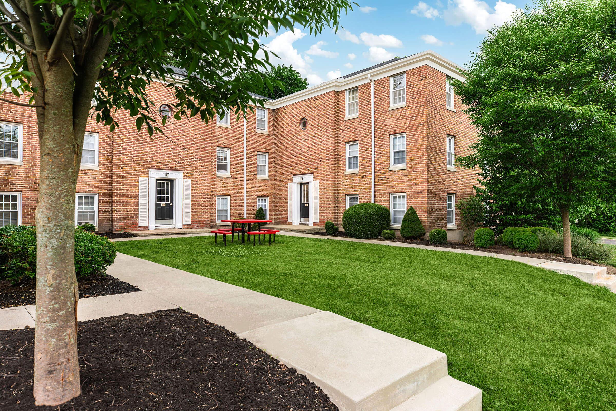 a large brick building with grass in front of a house