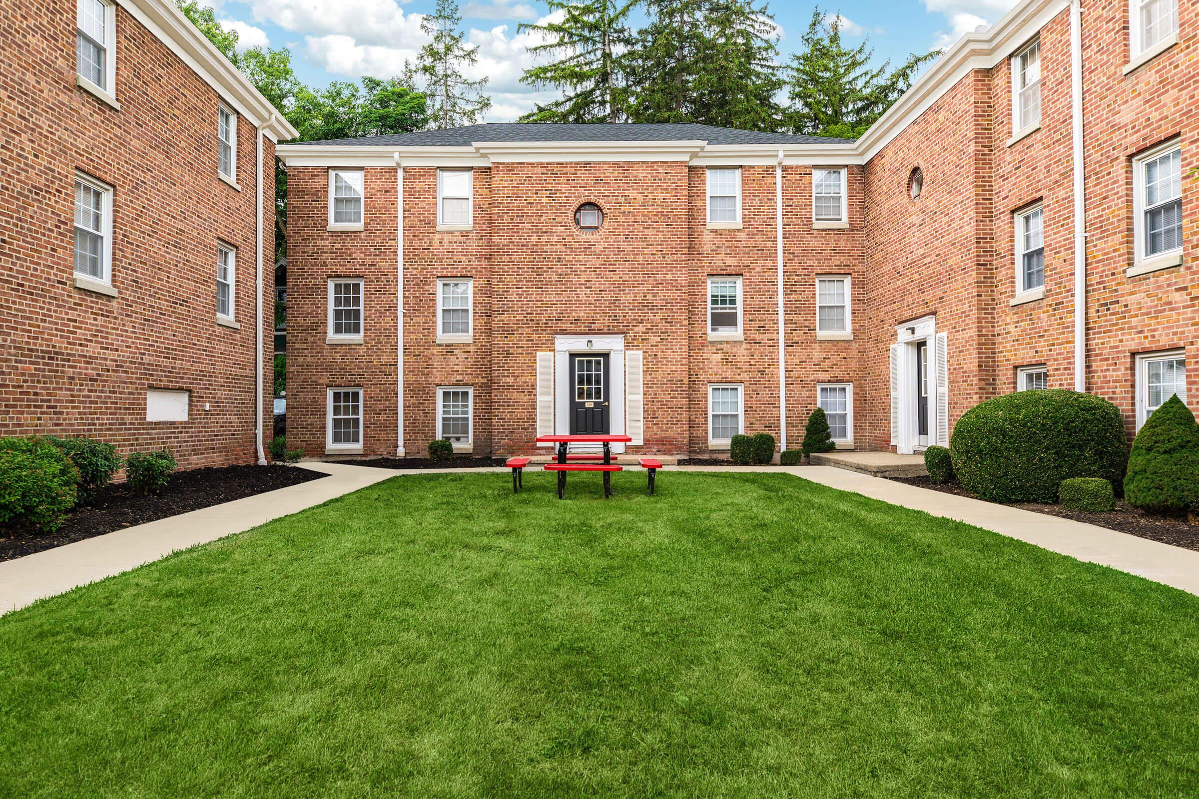 a large brick building with grass in front of a house