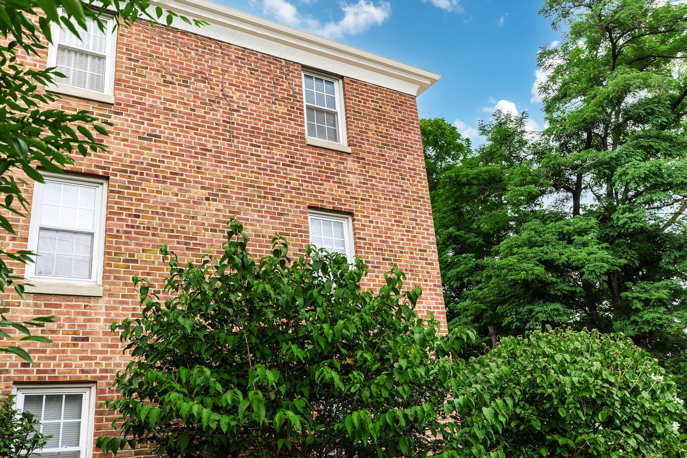 a house with bushes in front of a brick building