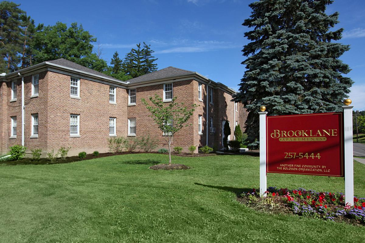 a large brick building with grass in front of a house