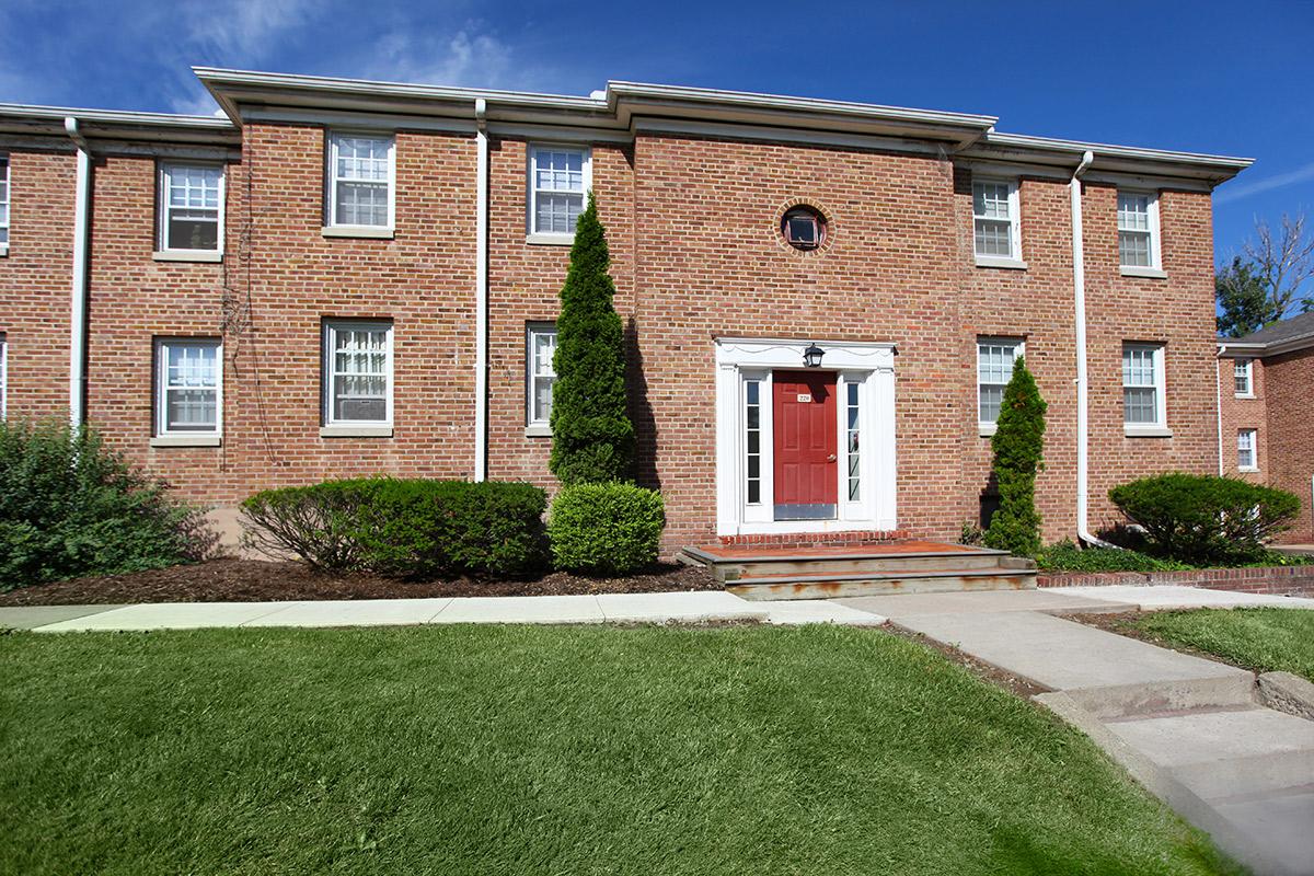 a large brick building with grass in front of a house