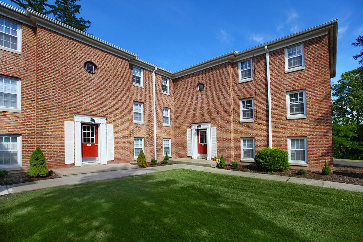 a large brick building with grass in front of a house