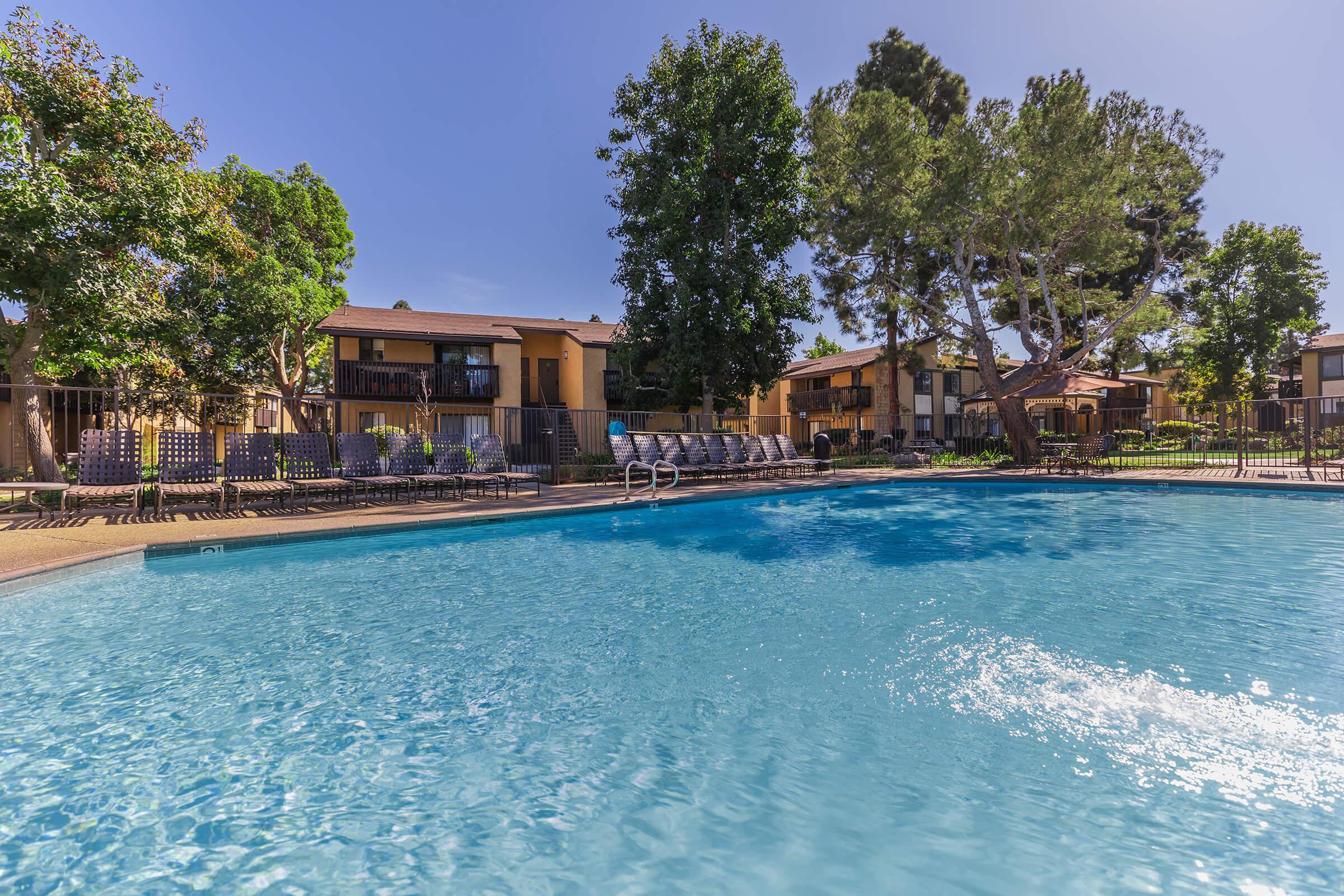 Pinecreek Village Apartments community pool with green trees