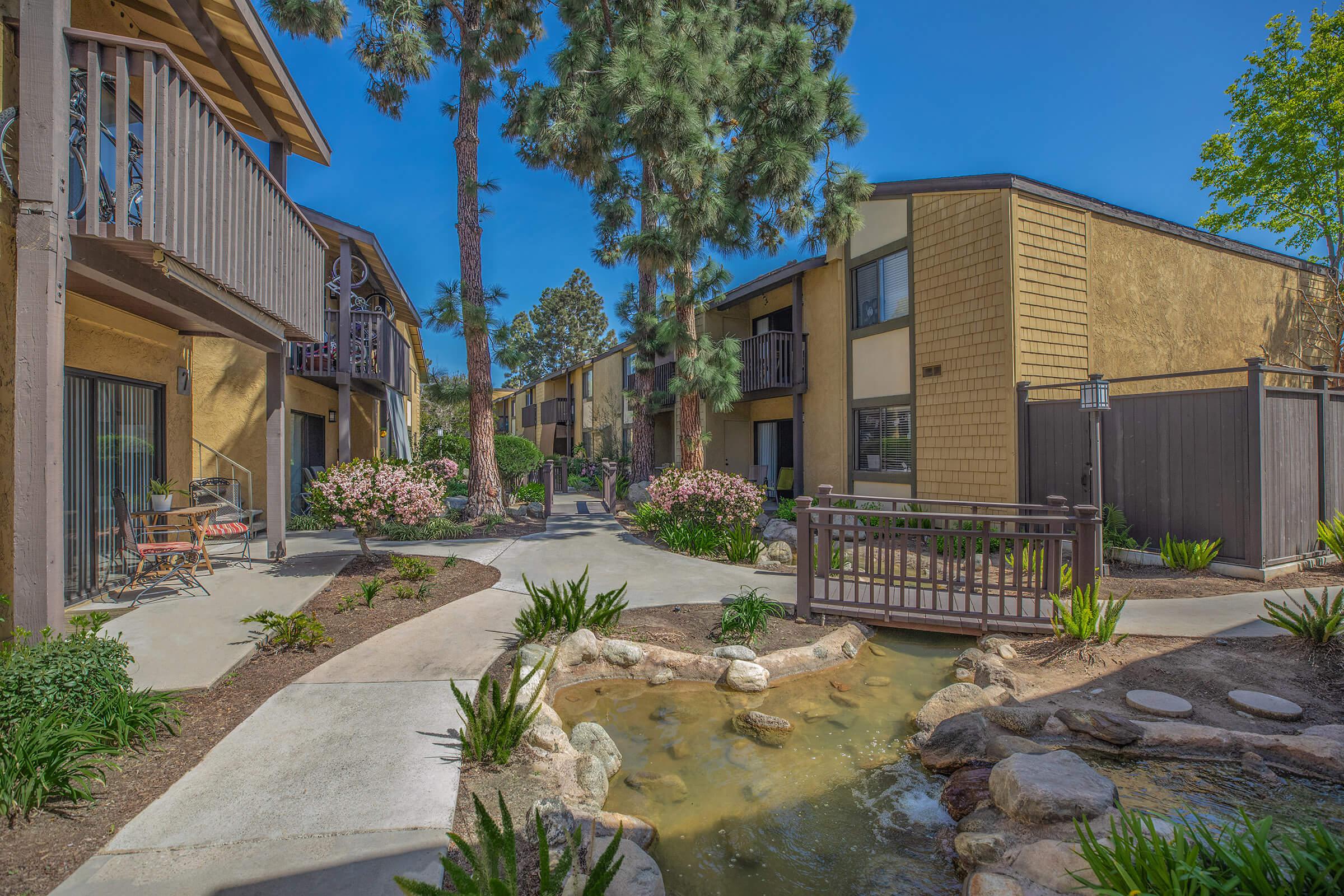 Pinecreek Village Apartments community building with green landscaping