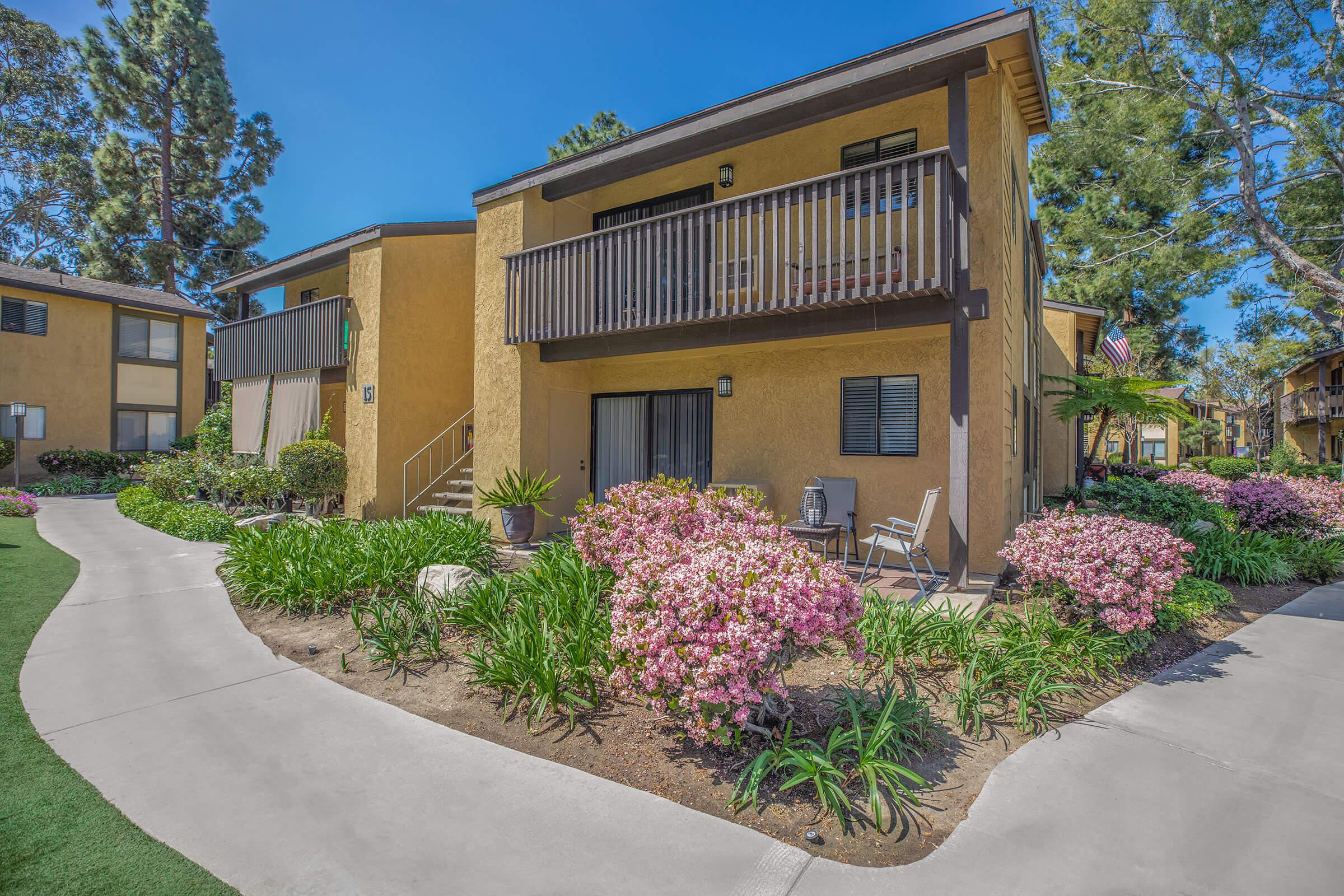 Pinecreek Village Apartments community building with pink flowers