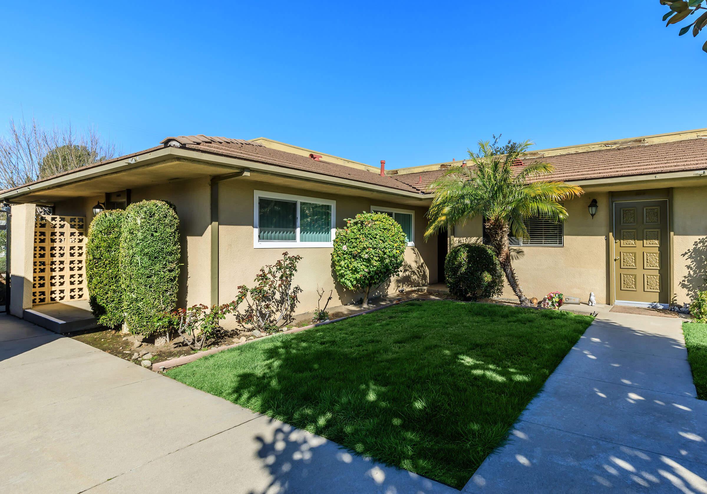 a house with a lawn in front of a brick building