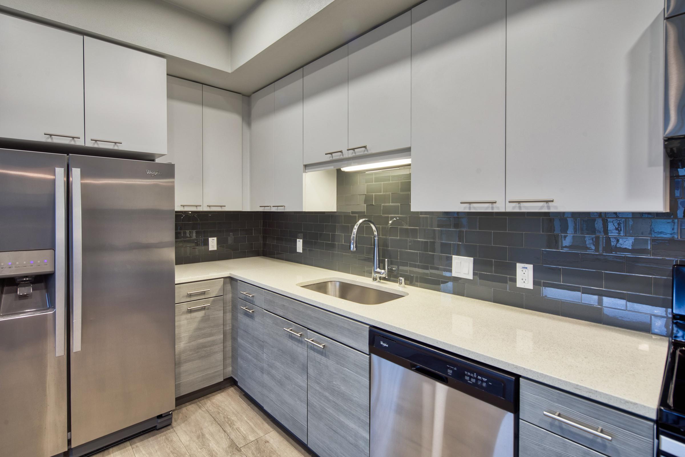 kitchen cabinets with brushed nickel hardware, quartz countertops, and subway tile backsplash.