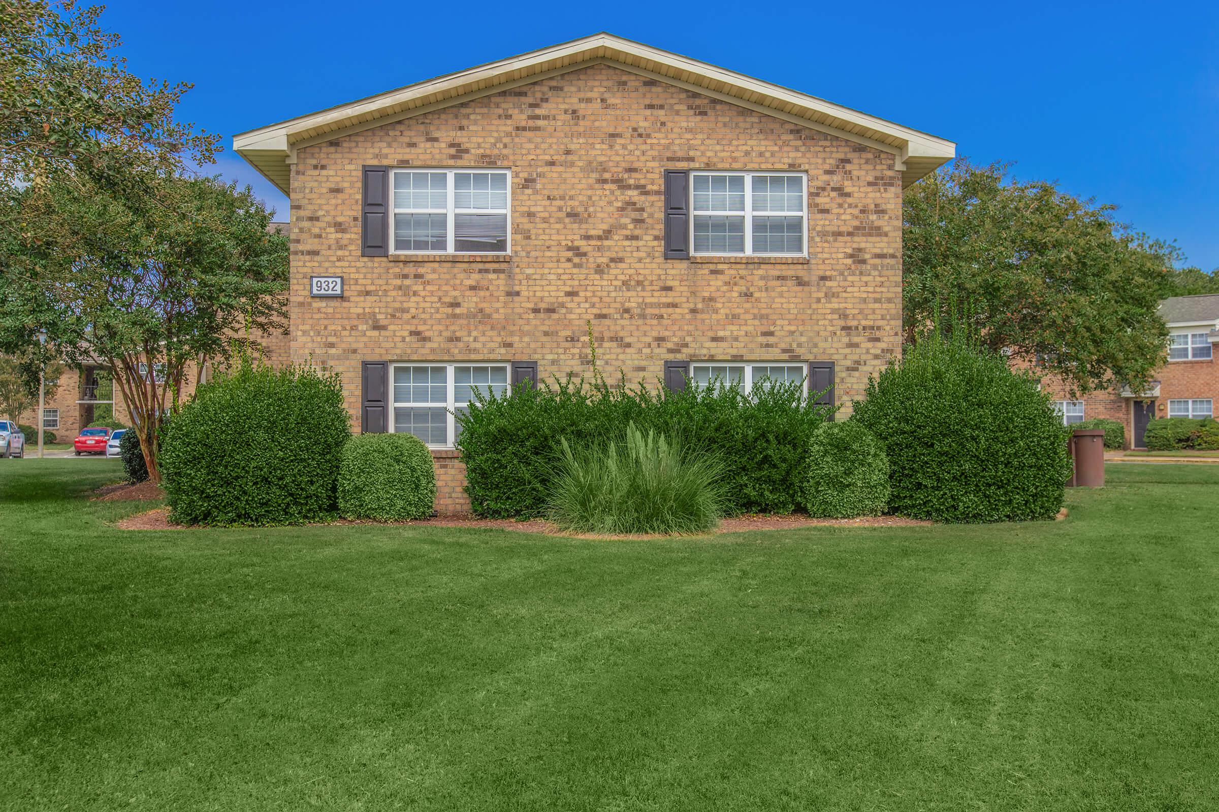 a large brick building with grass in front of a house