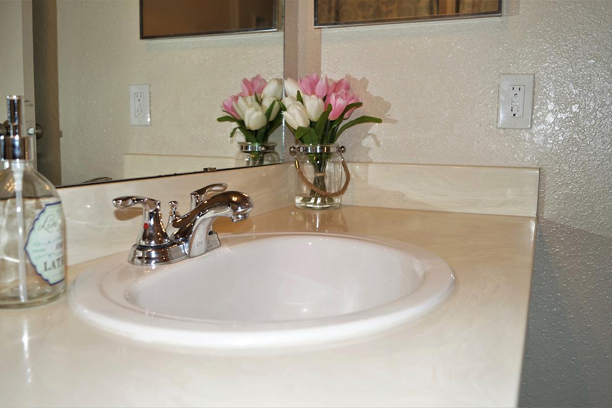 a white sink sitting next to a vase of flowers on a table