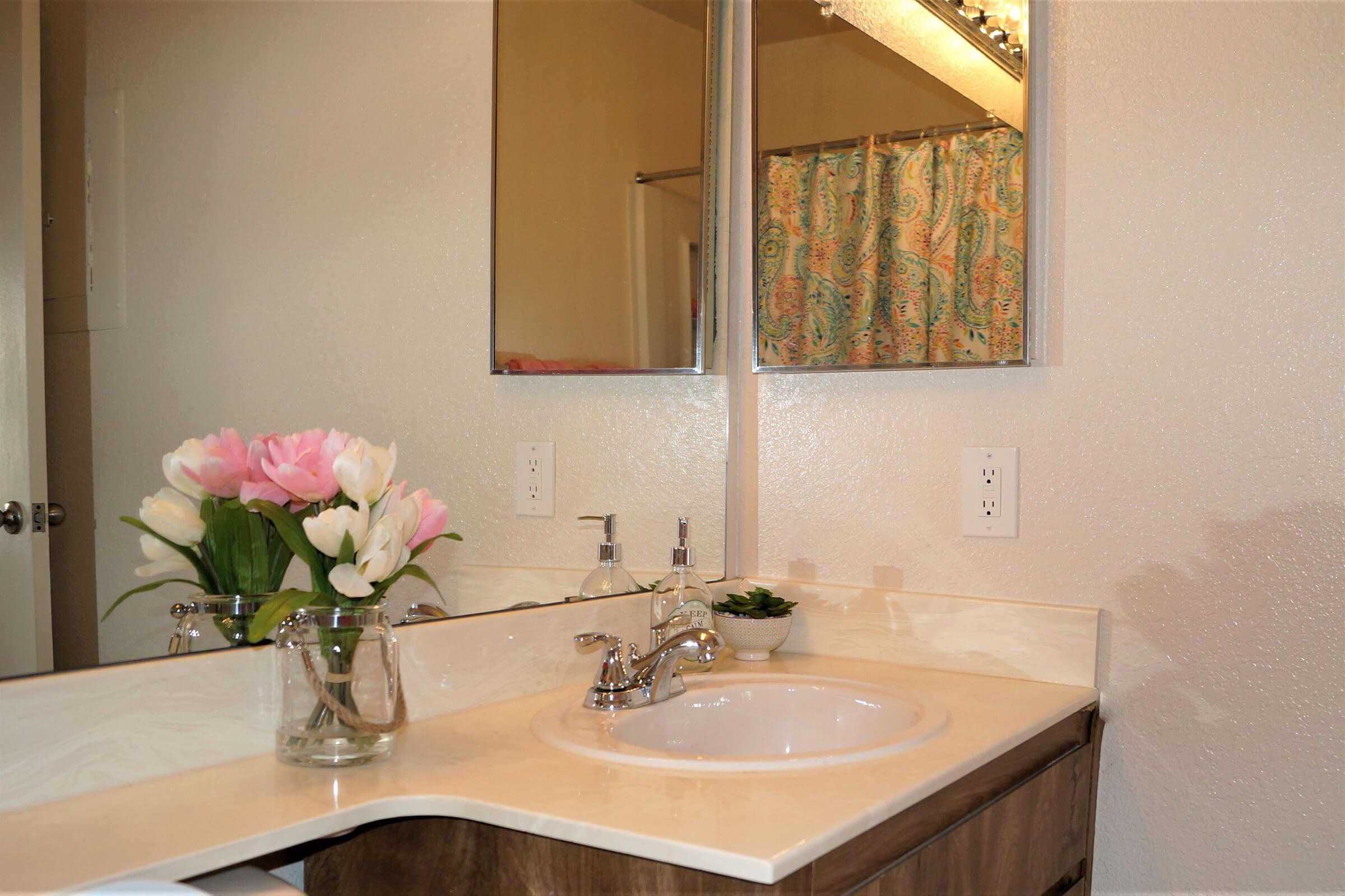 a white sink sitting under a mirror