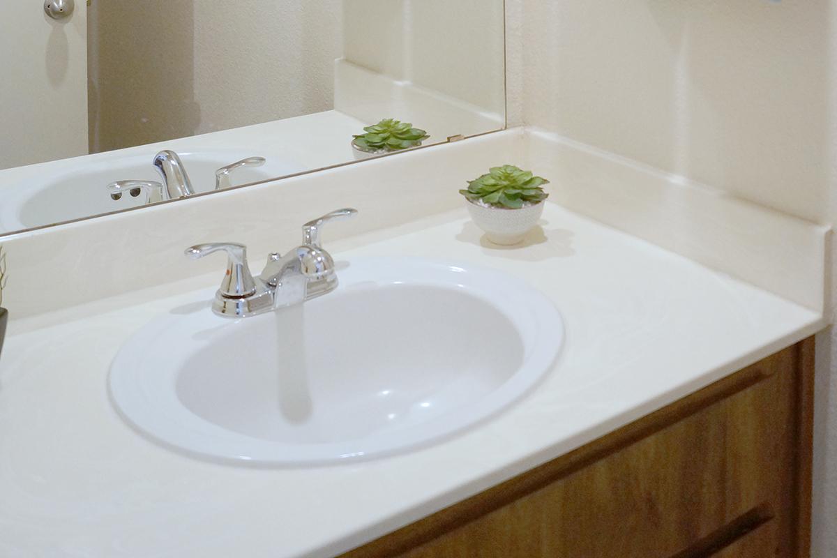 a white sink sitting under a mirror