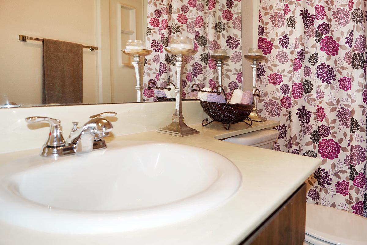 a white sink sitting under a mirror