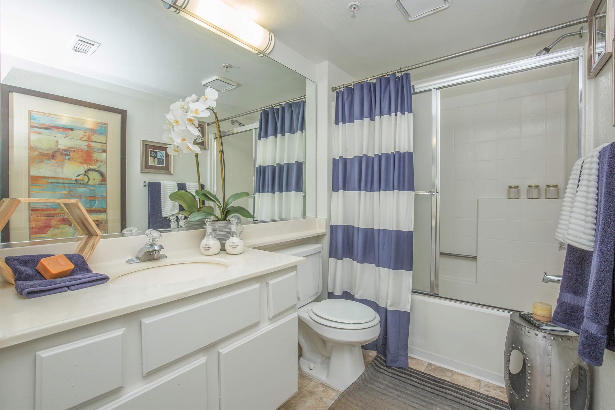 a bathroom with blue and white shower curtain over glass doors