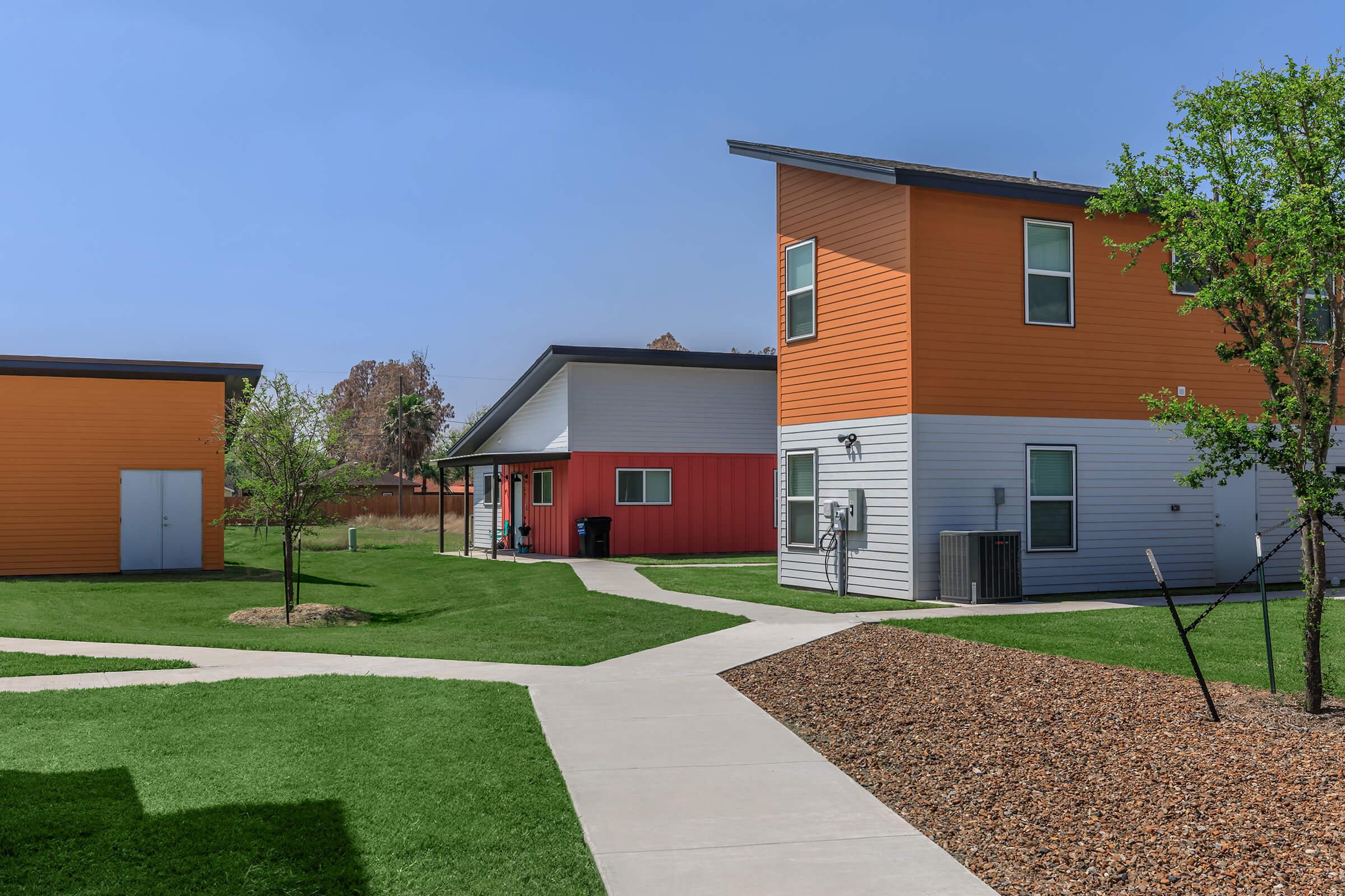 a house with a lawn in front of a brick building