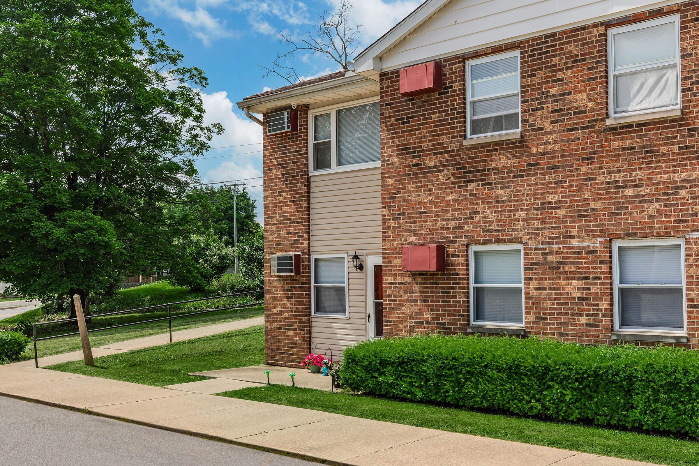 a house with bushes in front of a brick building