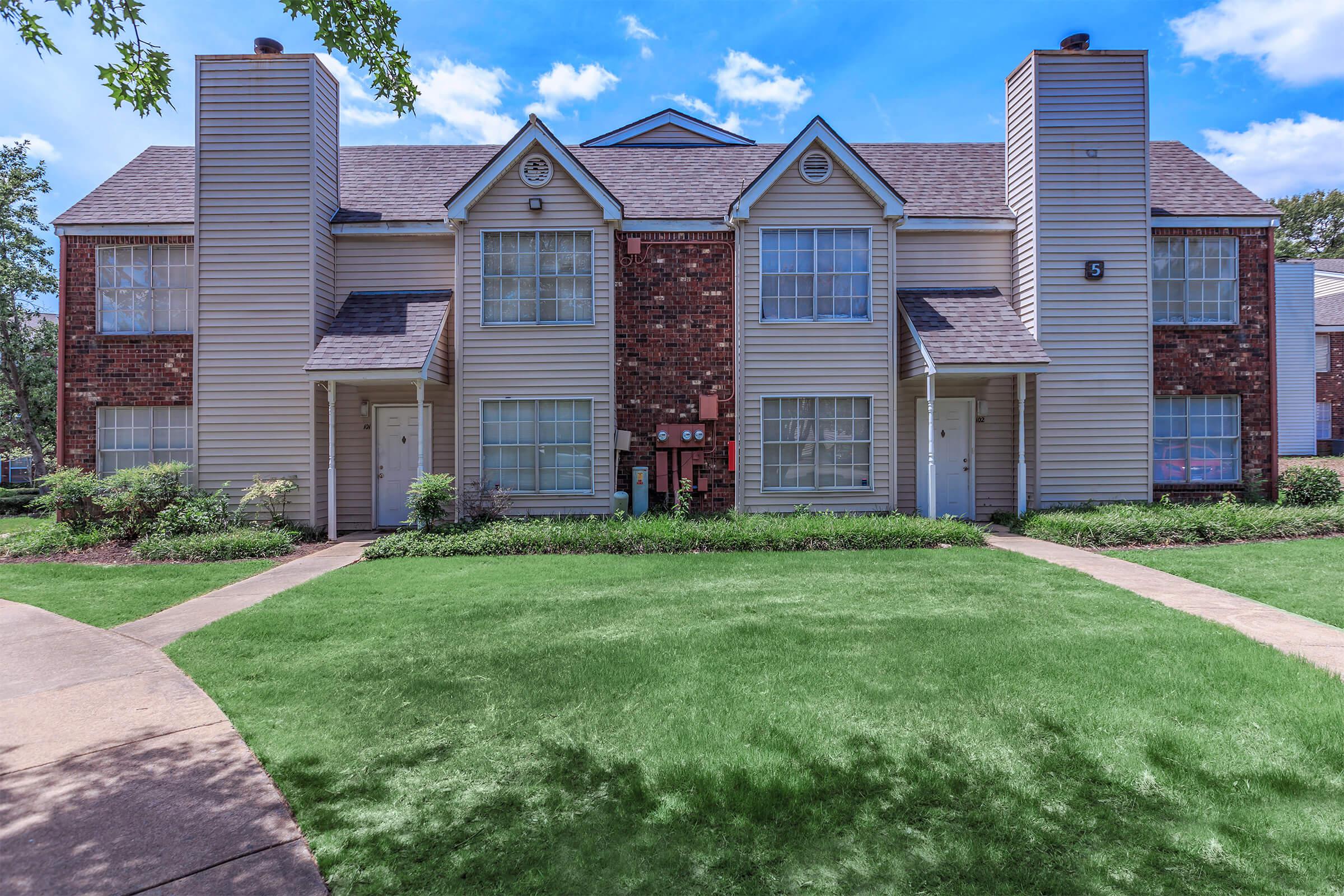 a house with a lawn in front of a brick building