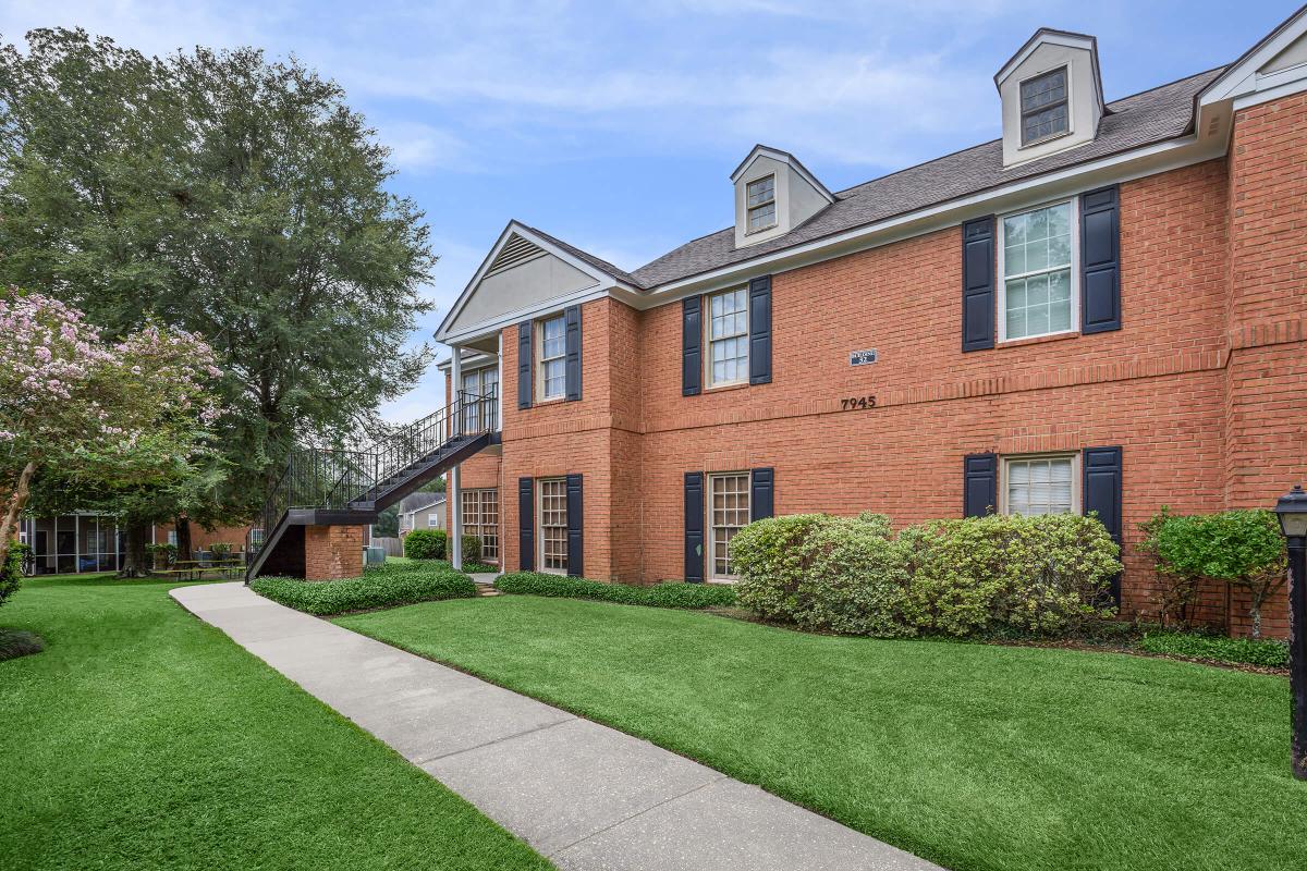 a large brick building with grass in front of a house