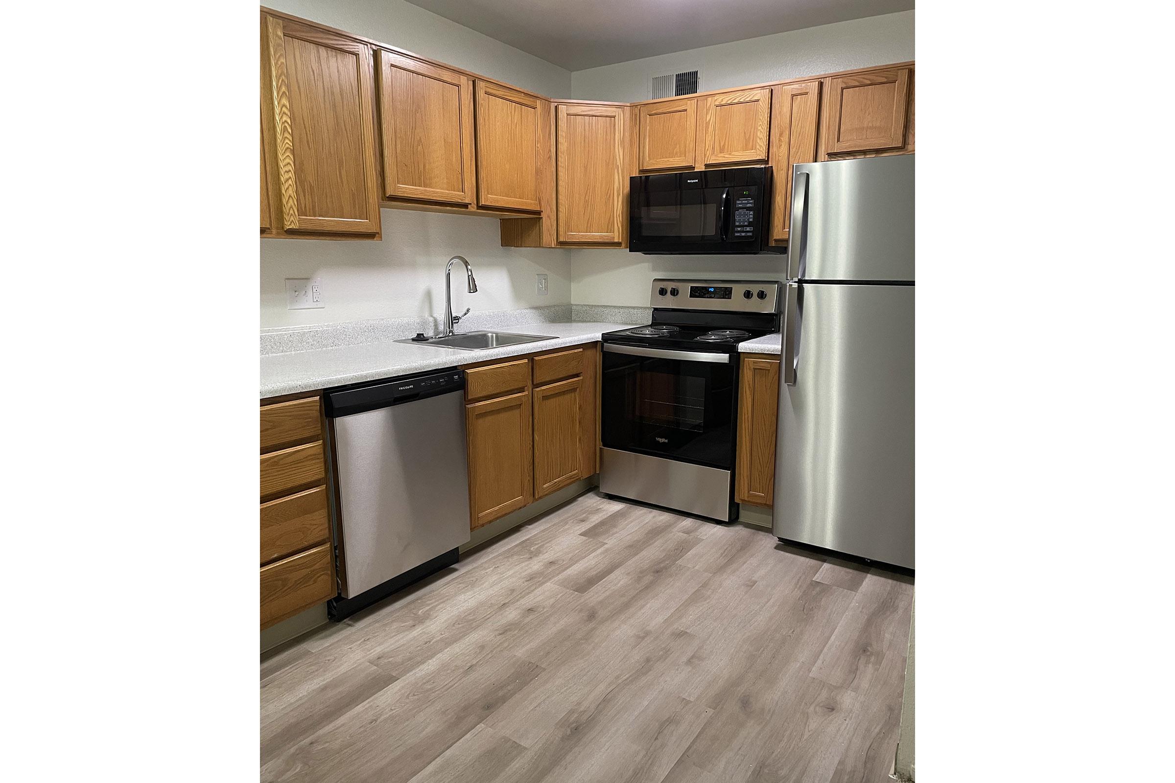 a large kitchen with stainless steel appliances and wooden cabinets