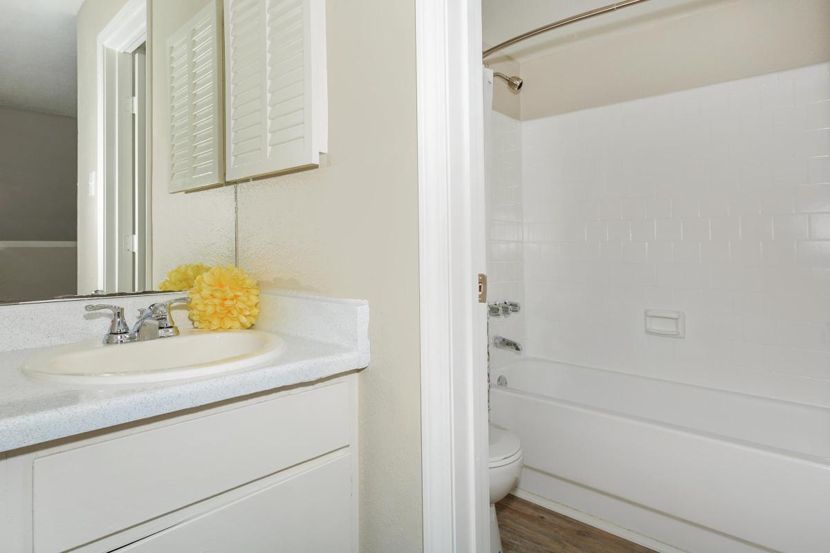 a white sink sitting under a mirror