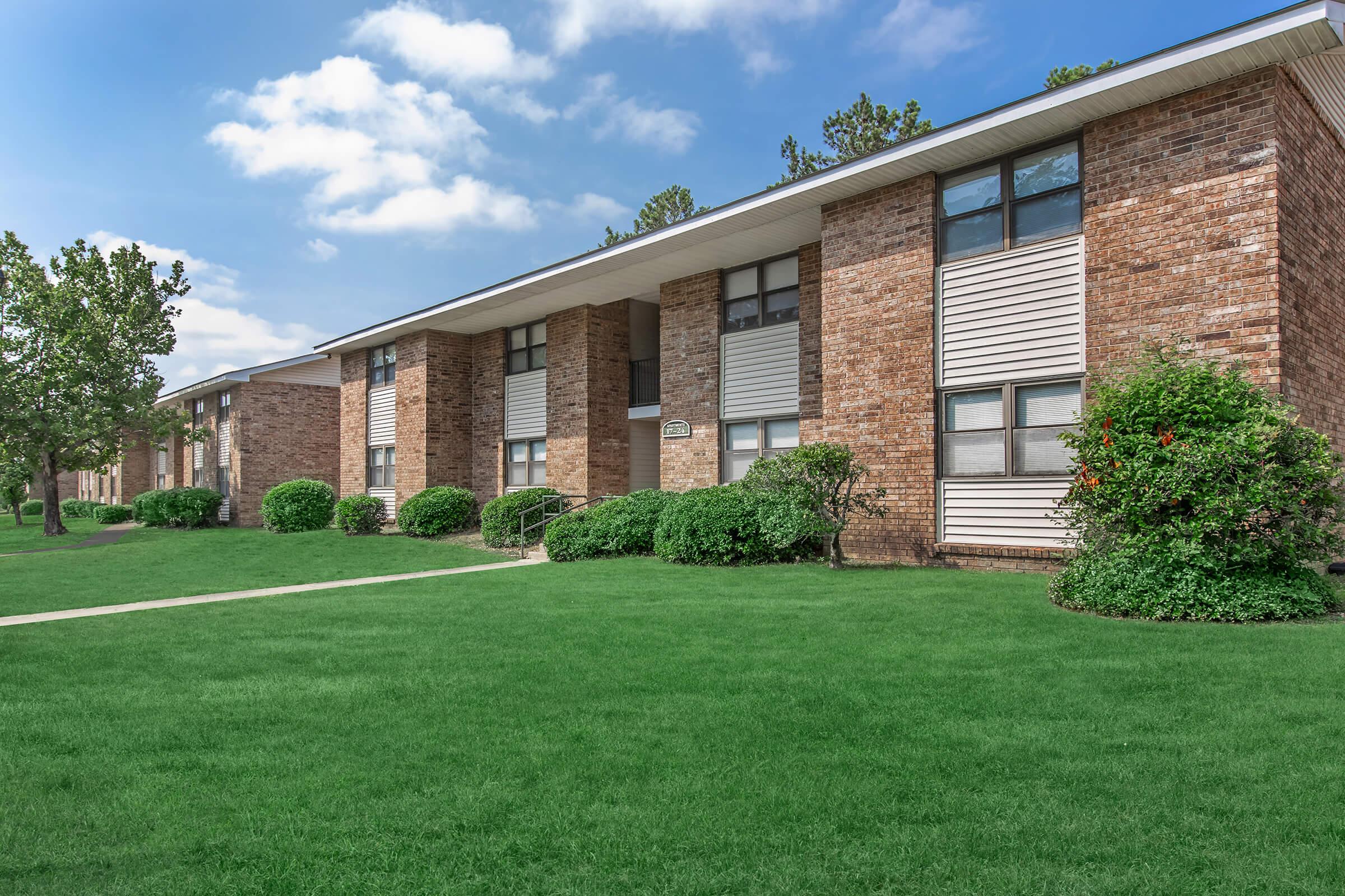 a large brick building with grass in front of a house