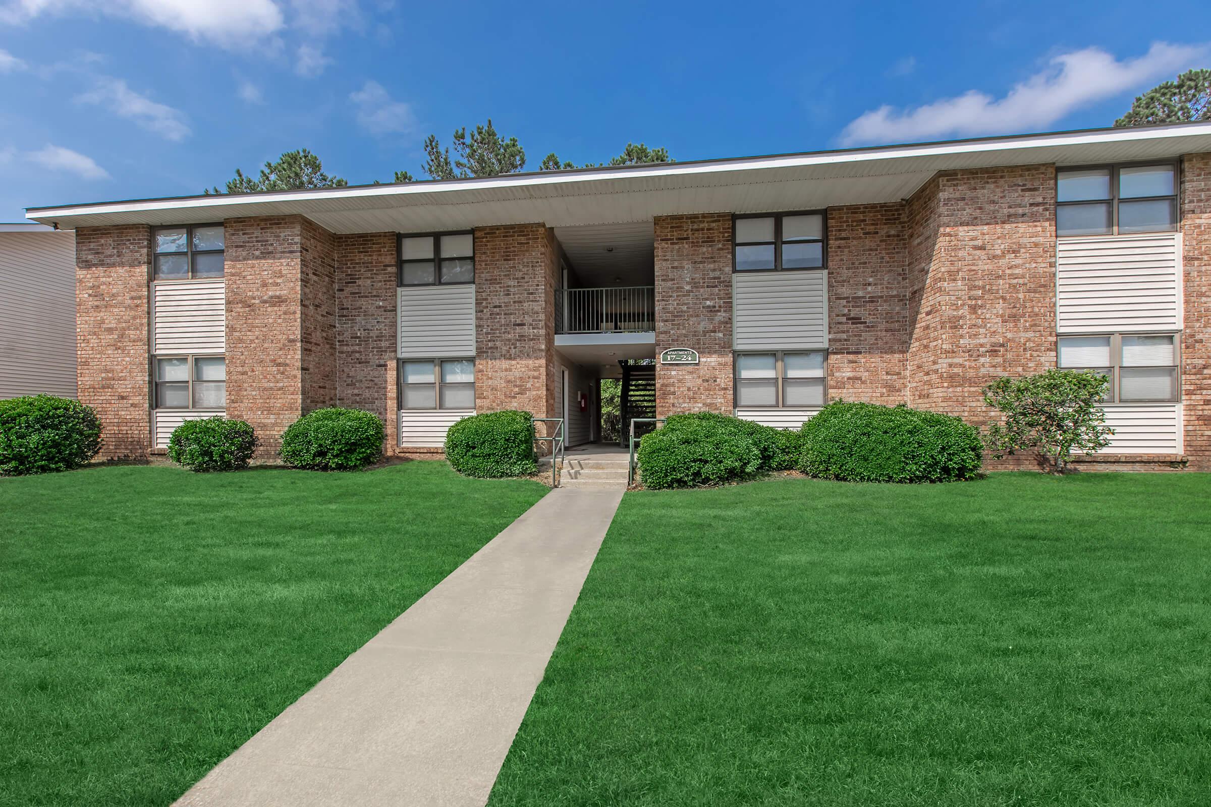 a large brick building with green grass in front of a house