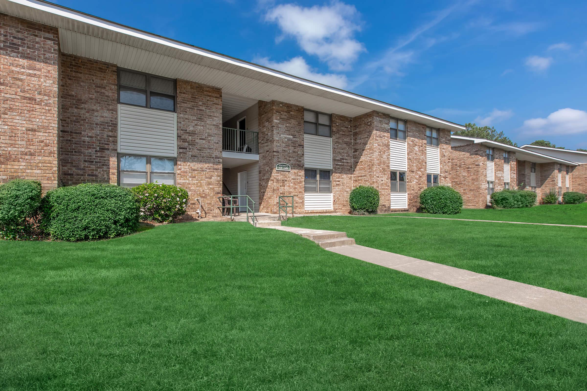 a large brick building with grass in front of a house