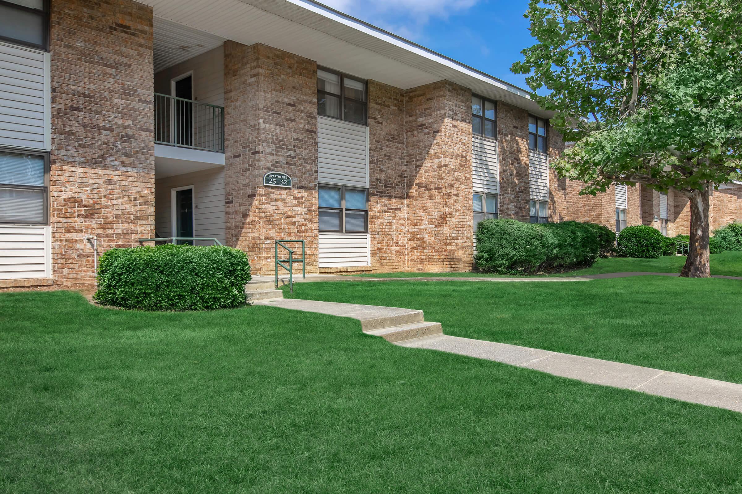 a house with a lawn in front of a brick building