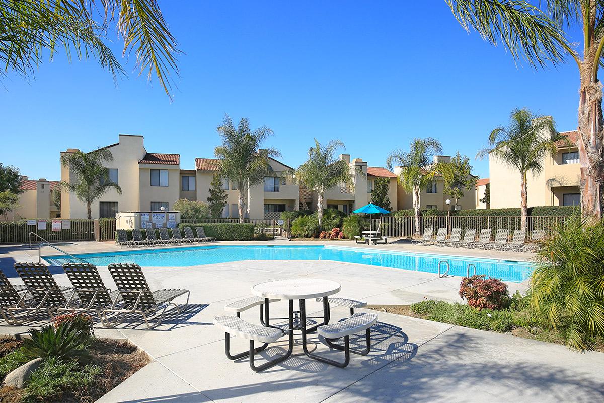 a group of lawn chairs sitting on a bench in front of a pool