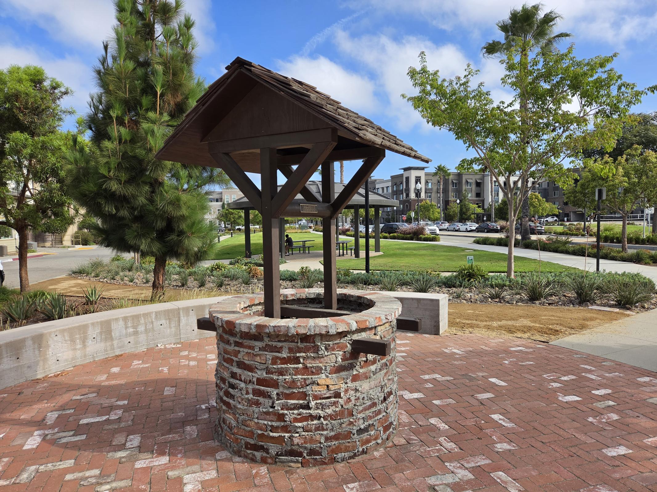 Discover a charming gathering spot featuring a rustic wishing well, surrounded by lush greenery and inviting pathways, perfect for relaxation and community connections in our vibrant apartment community.