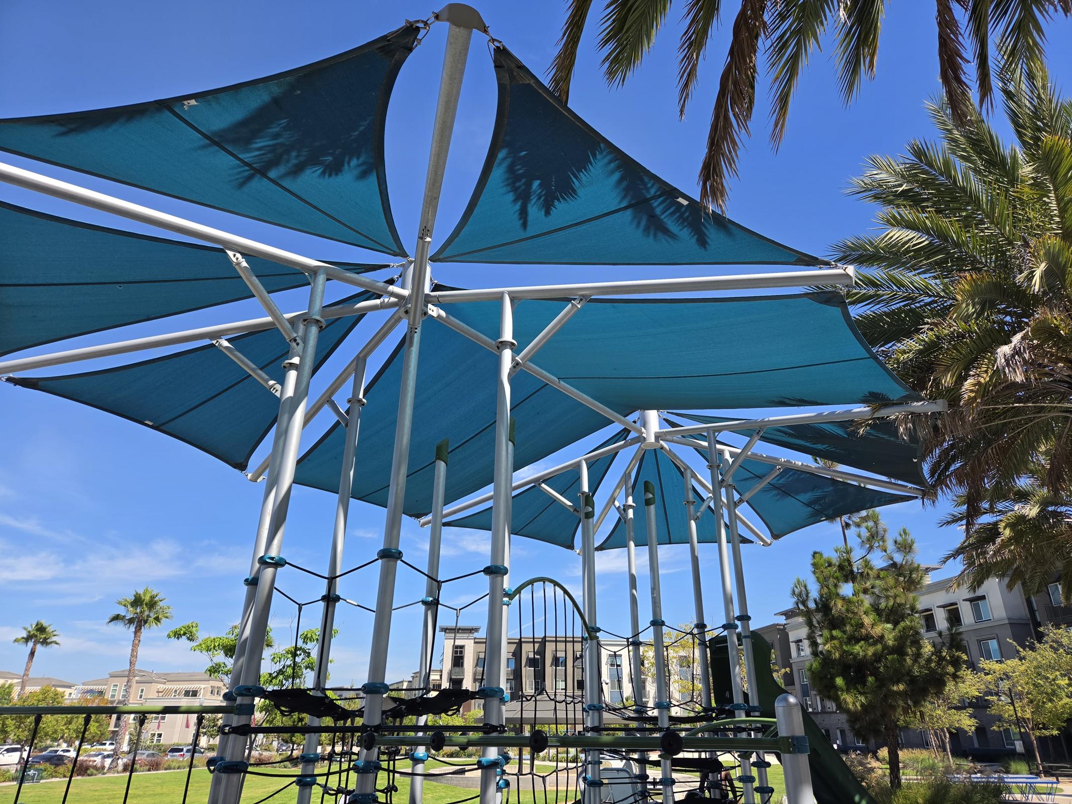 Discover a vibrant community where fun meets relaxation, featuring a shaded playground surrounded by lush palms—perfect for sunny days and joyful gatherings.