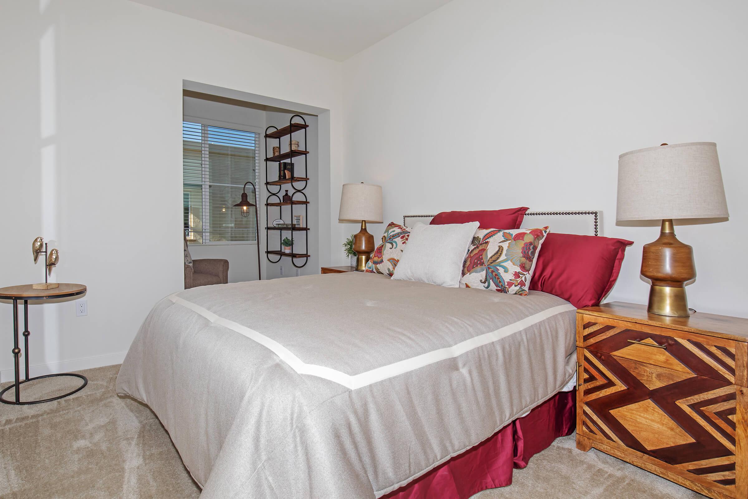 furnished carpeted bedroom with red pillows