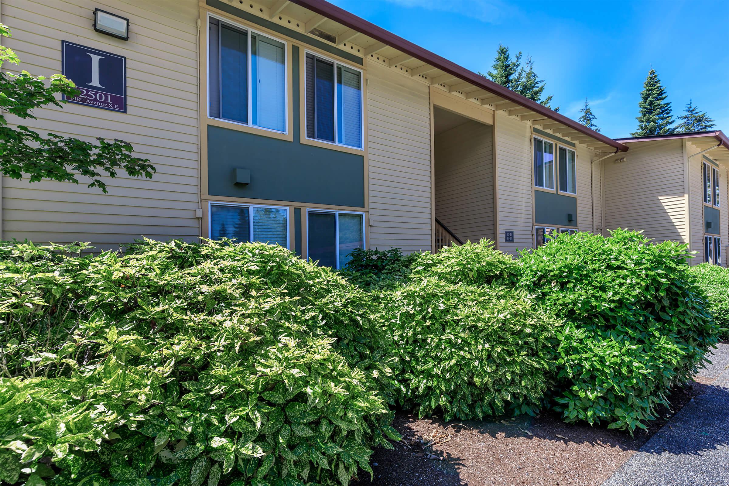 a house with bushes in front of a brick building